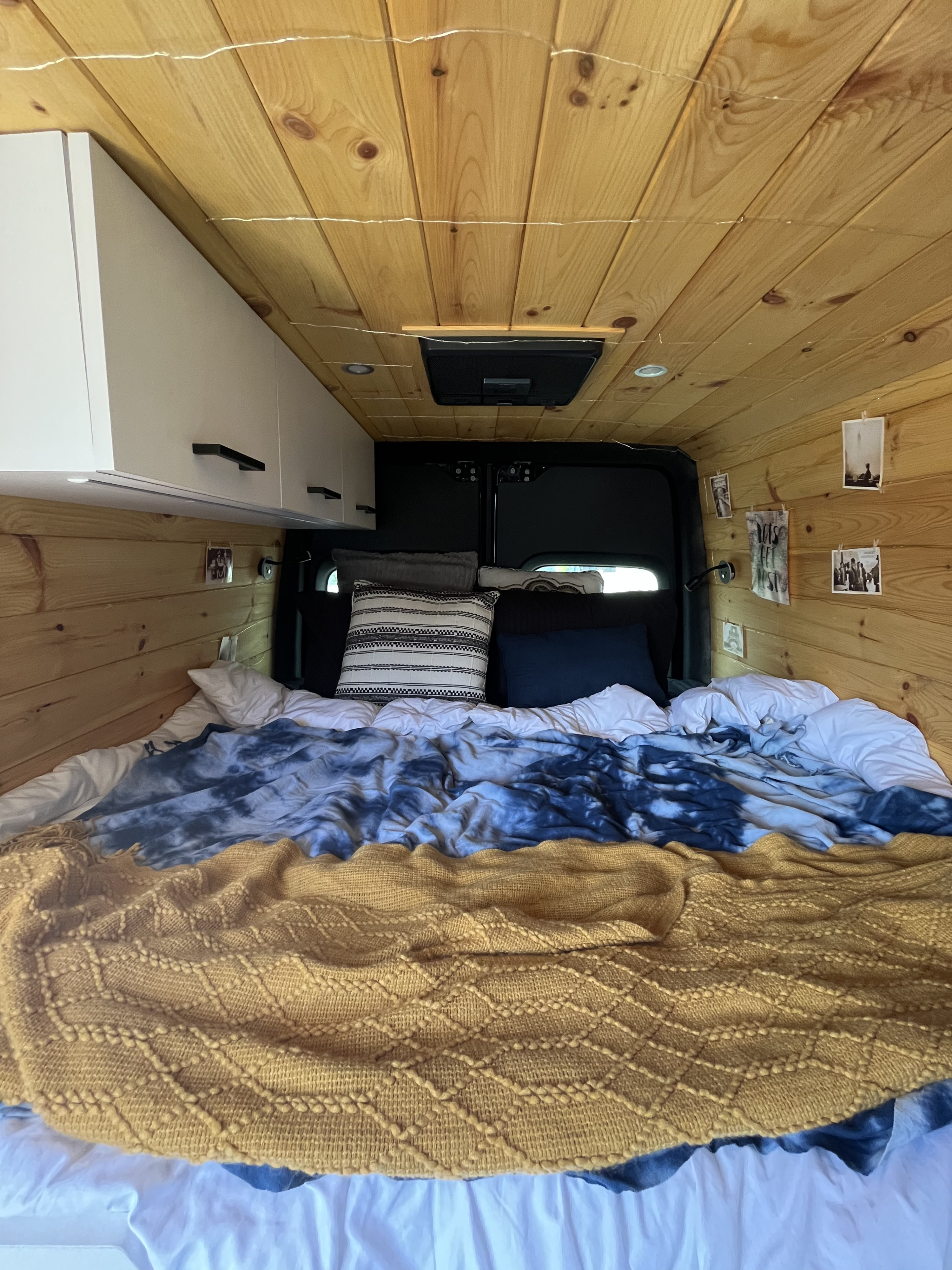 Inviting rv rental sleeping area featuring wood paneling, a comfy bed, and practical overhead cabinets.. Mercedes-Benz Sprinter 419 LWB High Roof 2019