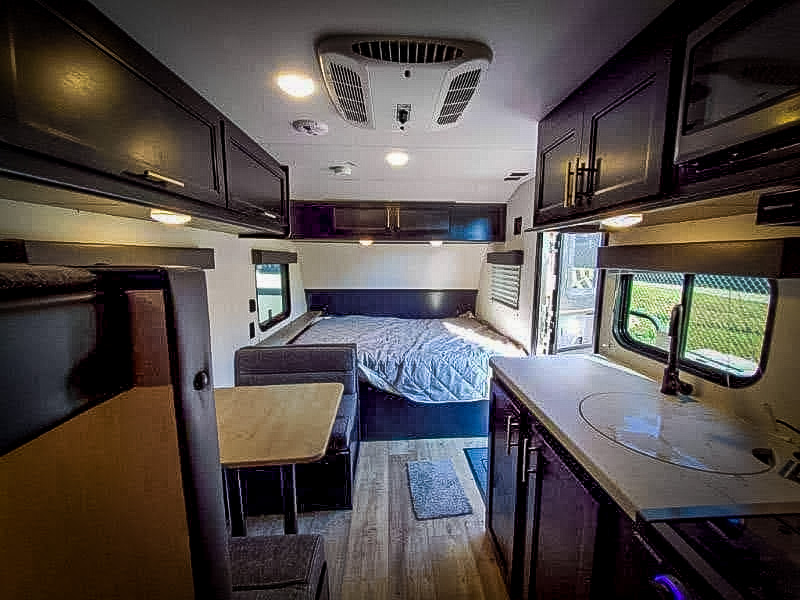 Inside this RV rental, see the cozy bedroom, a comfortable dinette, and a functional kitchenette with a sink.. Forest River Cherokee Wolf Pup 2022