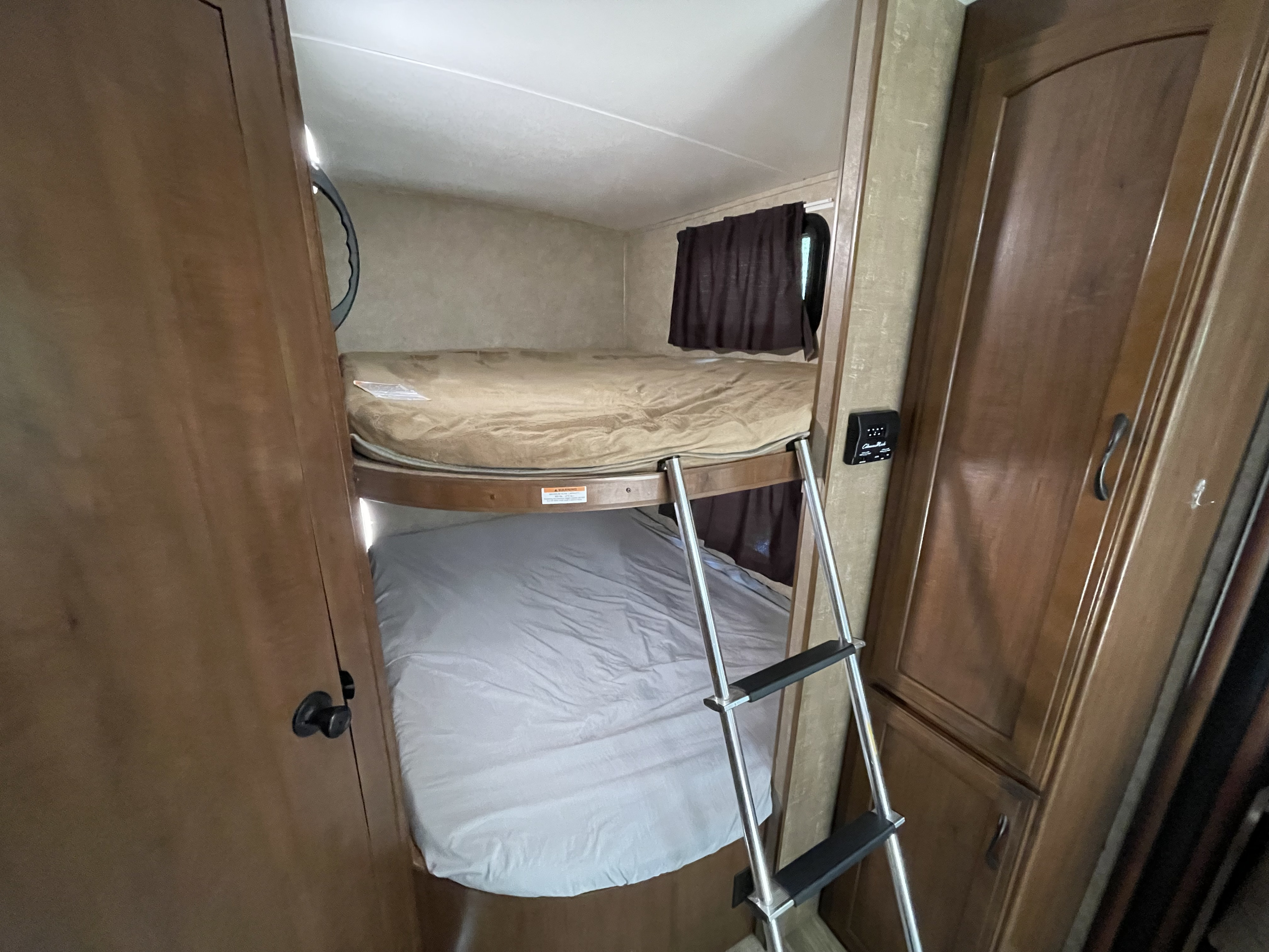 RV rental interior showing comfortable bunk beds. A metal ladder provides access to the top bunk, ideal for compact sleeping.. Jayco White Hawk 2017