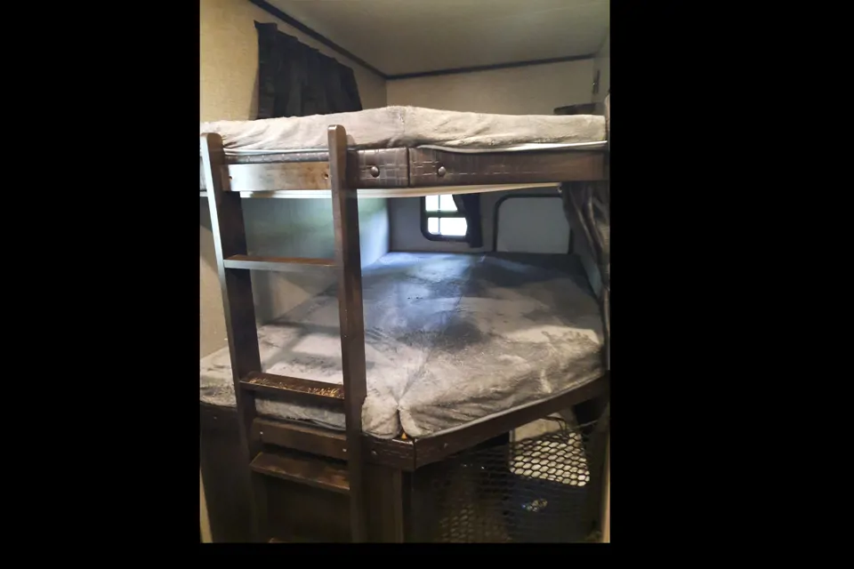 Interior view of an RV rental showing stacked bunk beds with gray mattresses and a ladder for access.. Jayco Jay Feather 2021