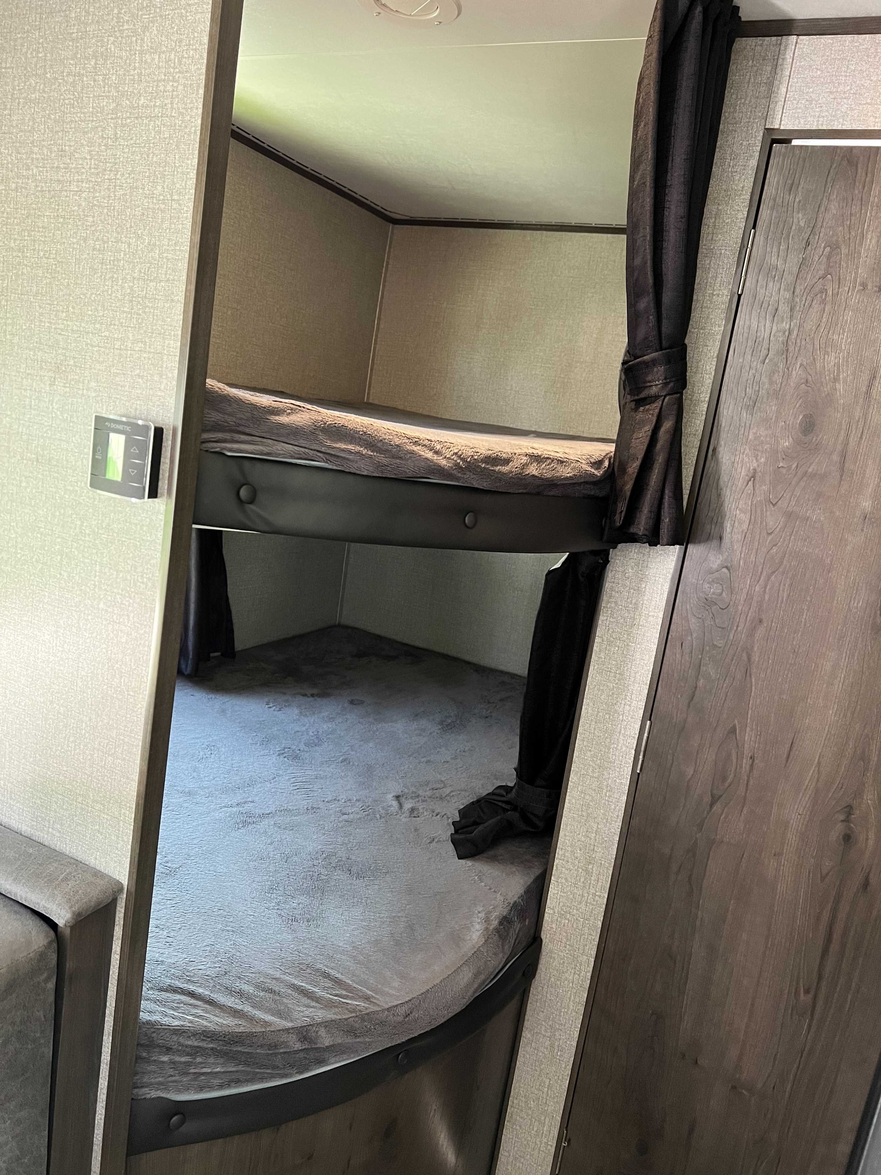 RV rental interior: cozy bunk beds with curtains and a Dometic control panel in a compact space.. Jayco Jay Flight SLX 2020