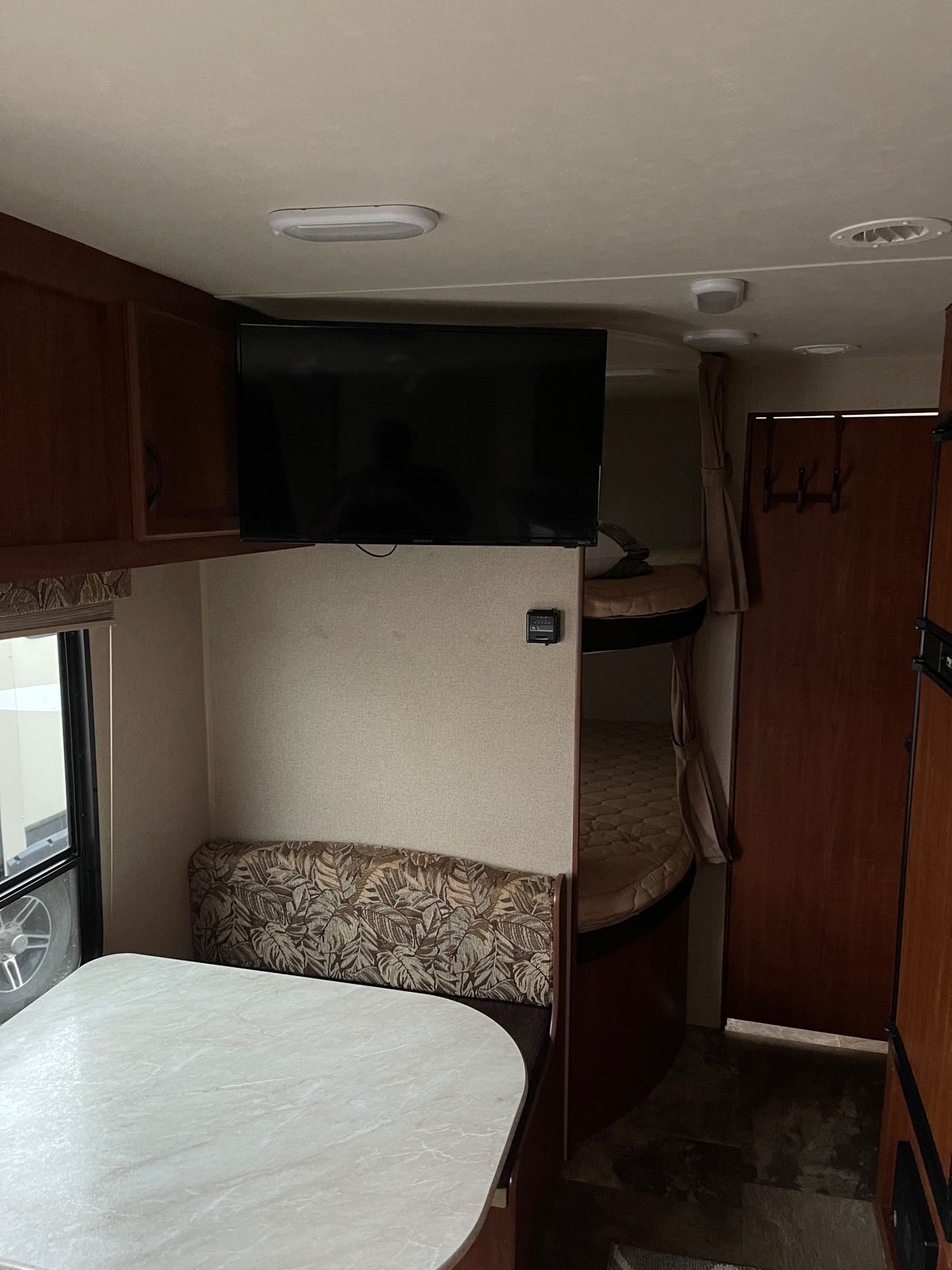 Cozy RV rental interior showing a dinette, mounted TV, and bunk beds, offering compact living for travel.. Jayco Jay Flight SLX 2018