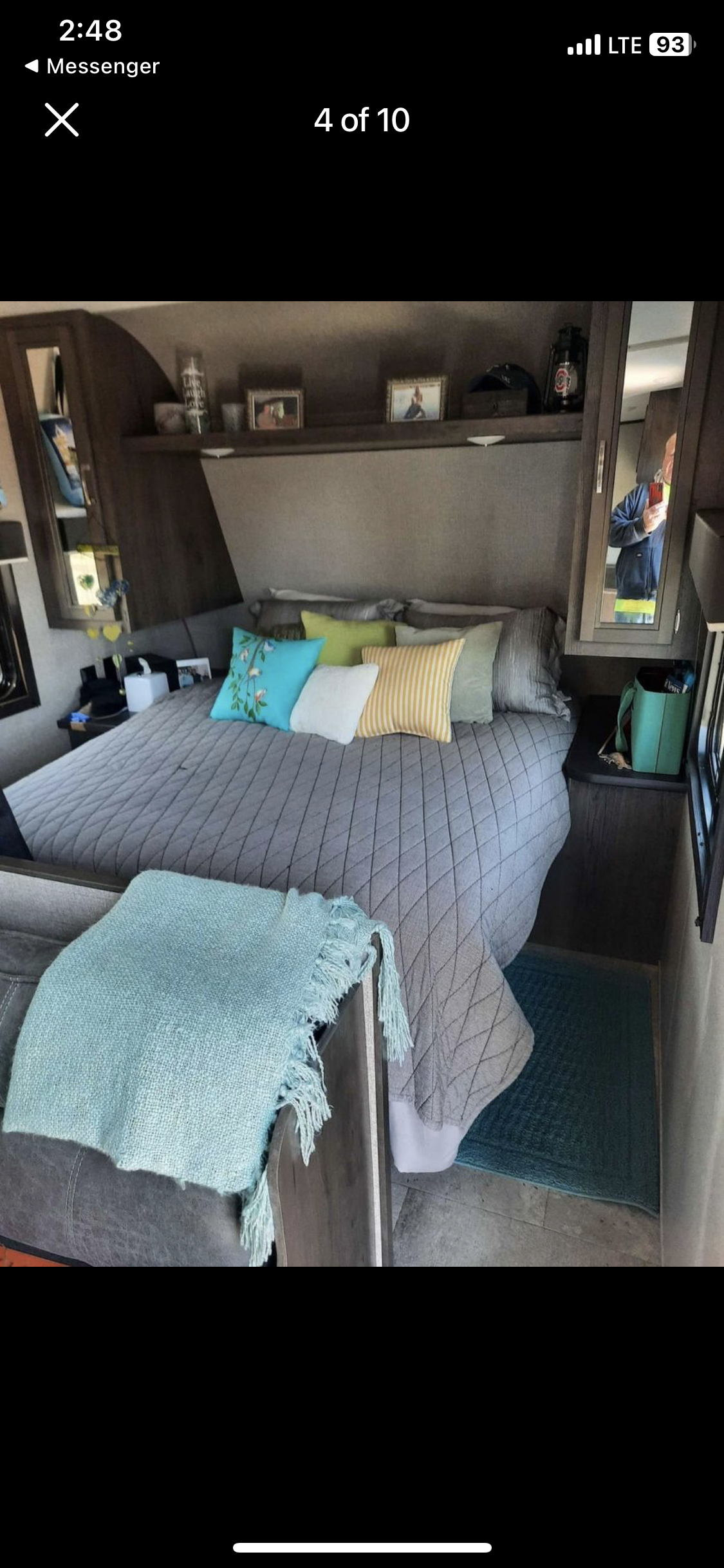 Inside an RV rental bedroom, featuring a neatly made bed with colorful pillows, overhead storage, and a soft blanket.. Jayco Jay Flight SLX 2021