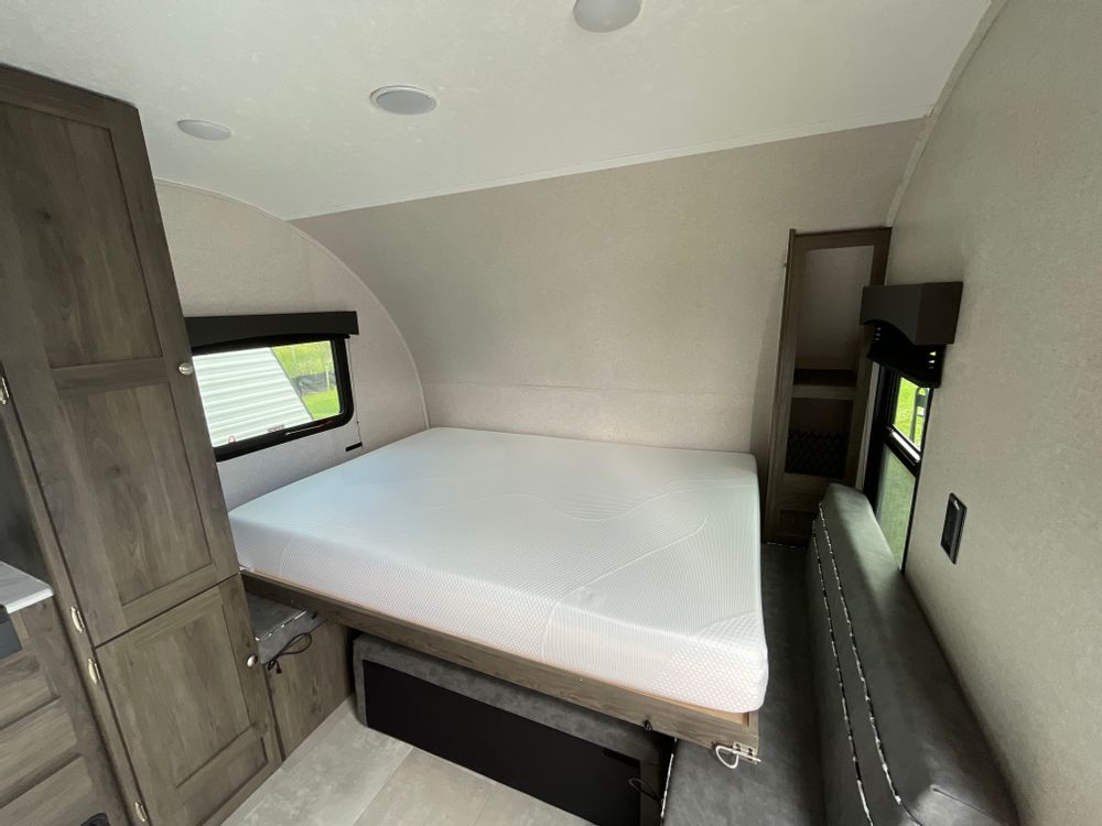 Step inside this clean RV rental, showcasing a comfy bed, gray couch, and storage – your perfect camper escape!. Independence Trail 188DBK 2022