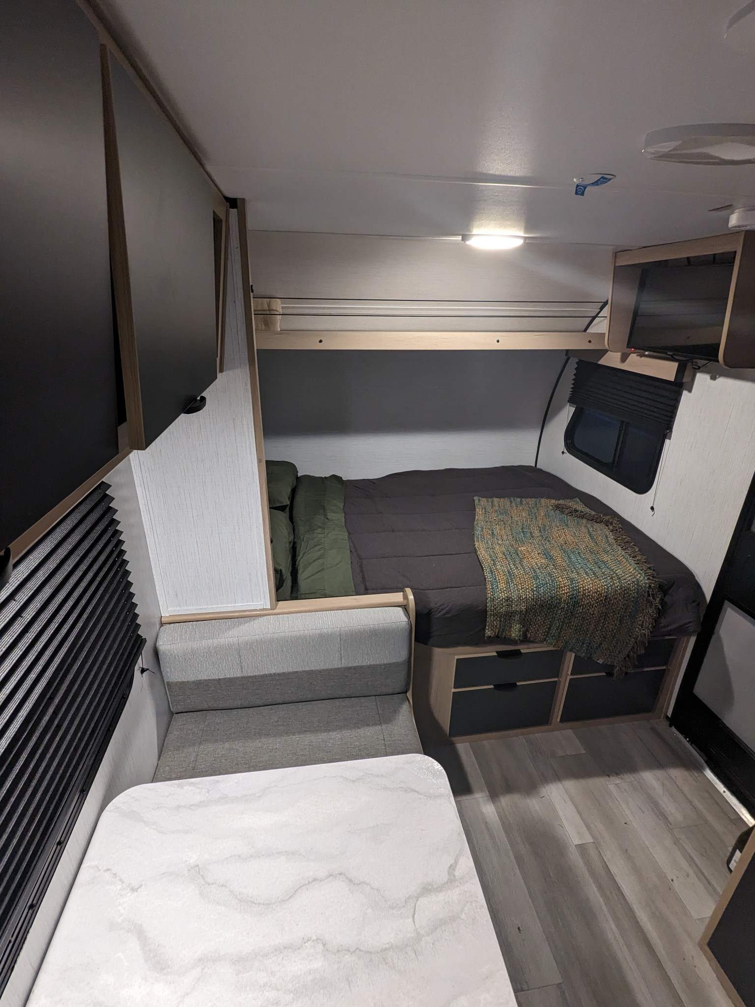 This RV rental interior showcases a compact bedroom with a bed & storage, alongside a comfy dinette with a white table.. Cruiser RV Hitch 2022