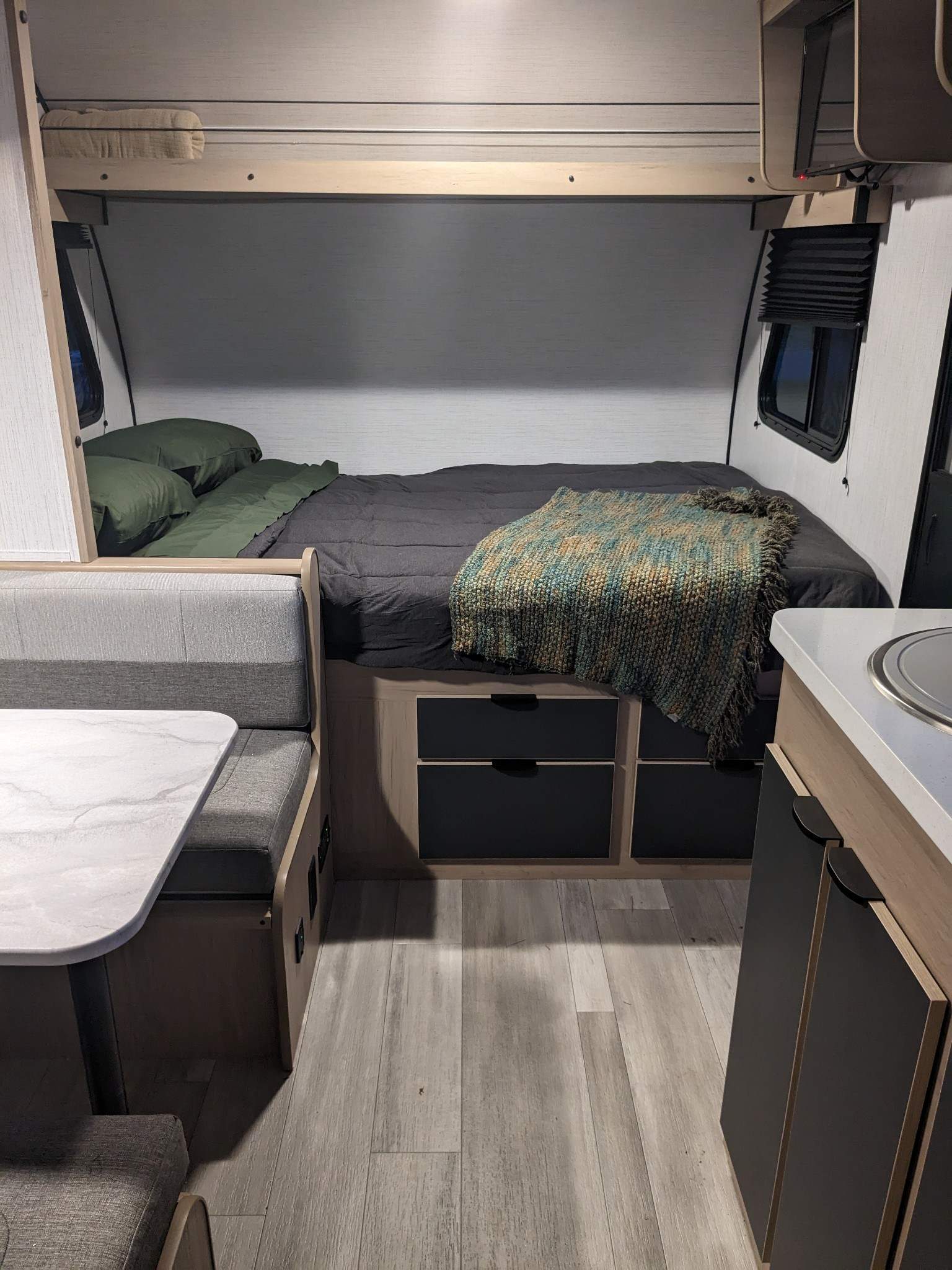 Cozy RV rental interior: bedroom, dinette, and compact kitchen with storage, light flooring, and bunk above.. Cruiser RV Hitch 2022