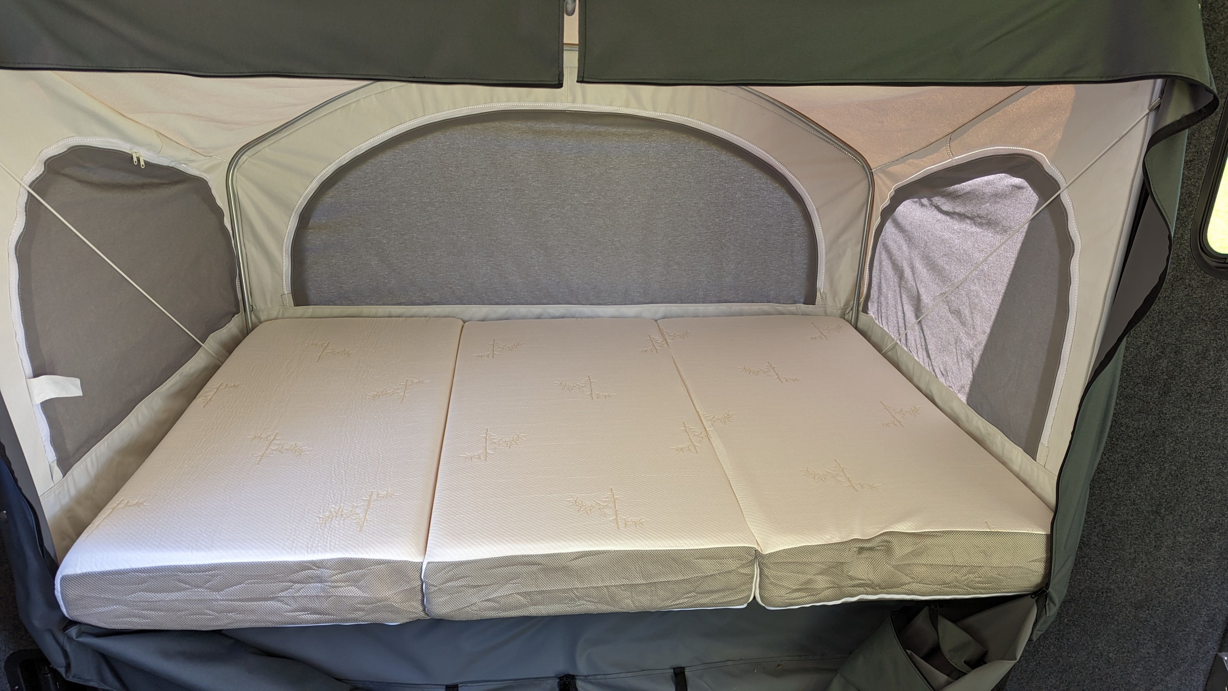 Interior of an RV rental sleeping area, featuring a tri-fold mattress and fabric walls with mesh windows, ready for a comfortable rest.. InTech RV Flyer 2022