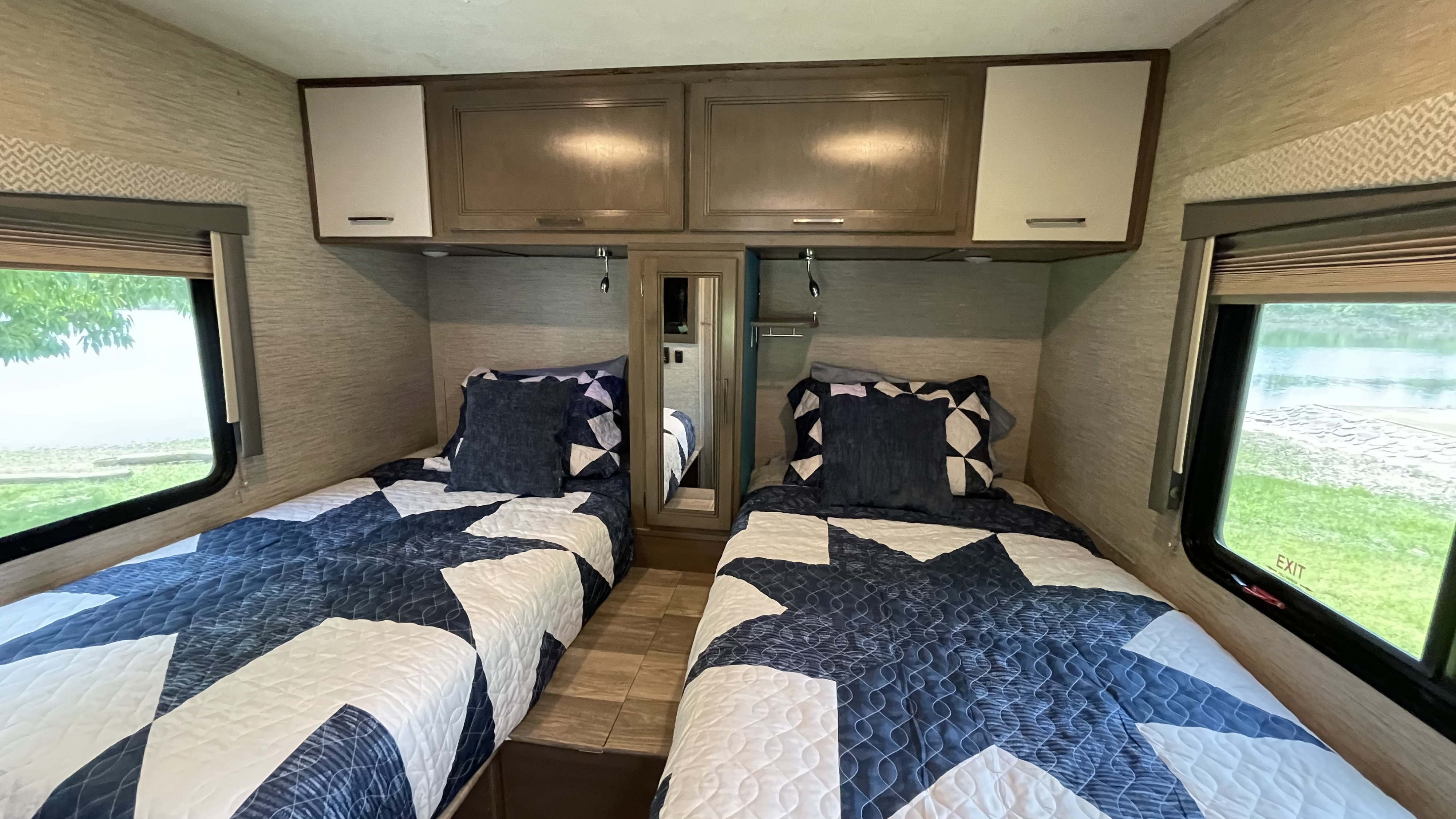 Cozy RV rental bedroom features twin beds, overhead cabinets, and scenic windows.. Thor Motor Coach Four Winds 2021