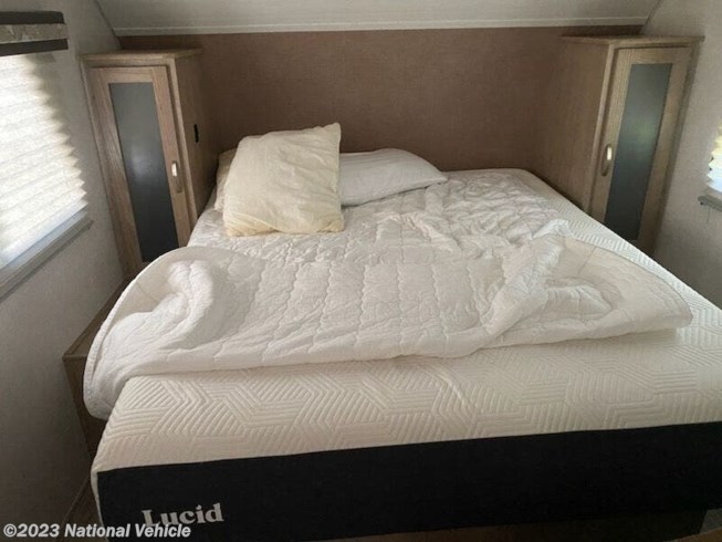 RV rental bedroom: Cozy bed with white comforter, pillows, and Lucid mattress, flanked by built-in cabinets.. Forest River R-Pod 2020