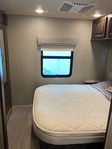 RV rental bedroom interior with a clean mattress, window, ceiling lights, and AC unit. Ready for comfortable trips.. Entegra Coach Emblem 2019