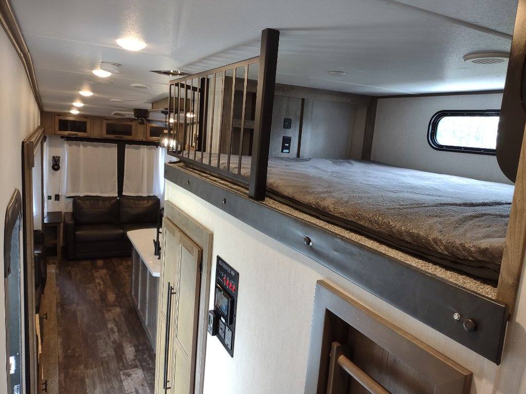 Spacious RV rental interior with a cozy loft bed, living area, and kitchen. Ideal for adventure travel.. Forest River Sabre 2021