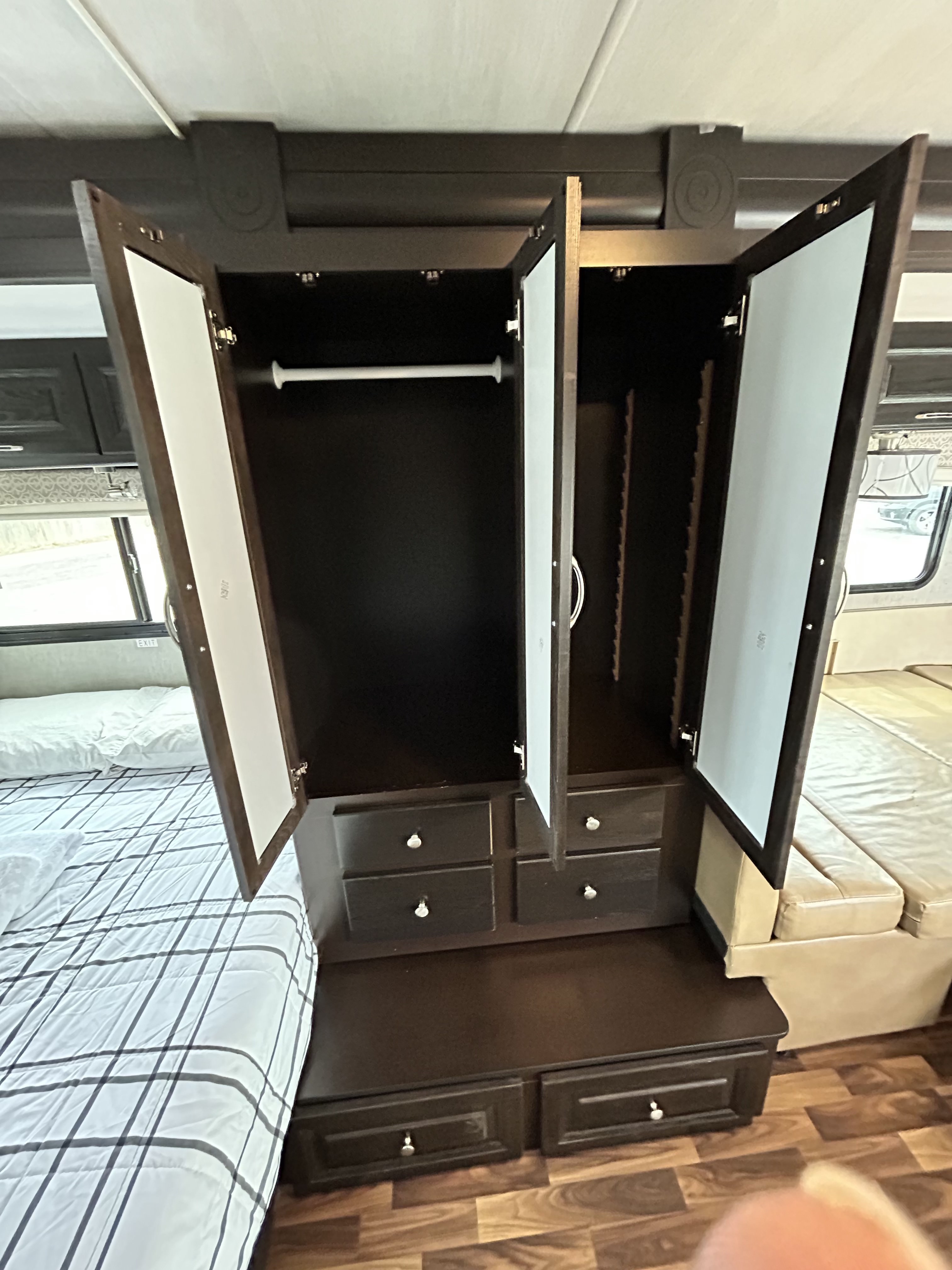 RV rental: Dark wood wardrobe with open doors showing a clothes rod, shelves, and drawers in a compact bedroom with a bed.. Nexus Phantom 2020
