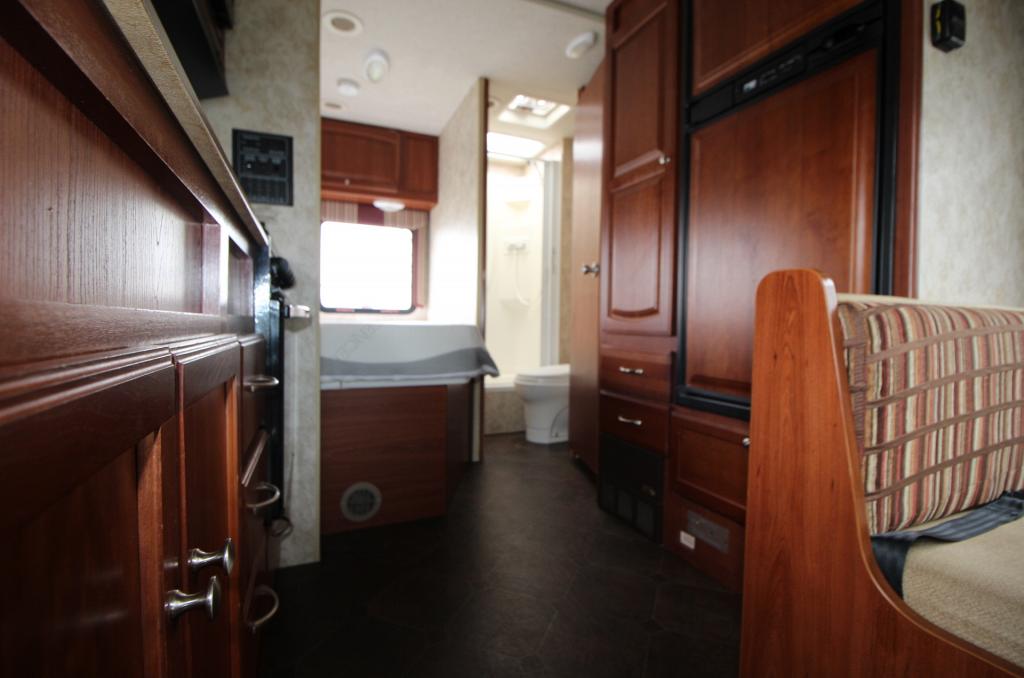 Spacious RV rental interior featuring full kitchen, cozy bedroom, and compact bathroom areas with warm wood finishes.. Winnebago Access 2011