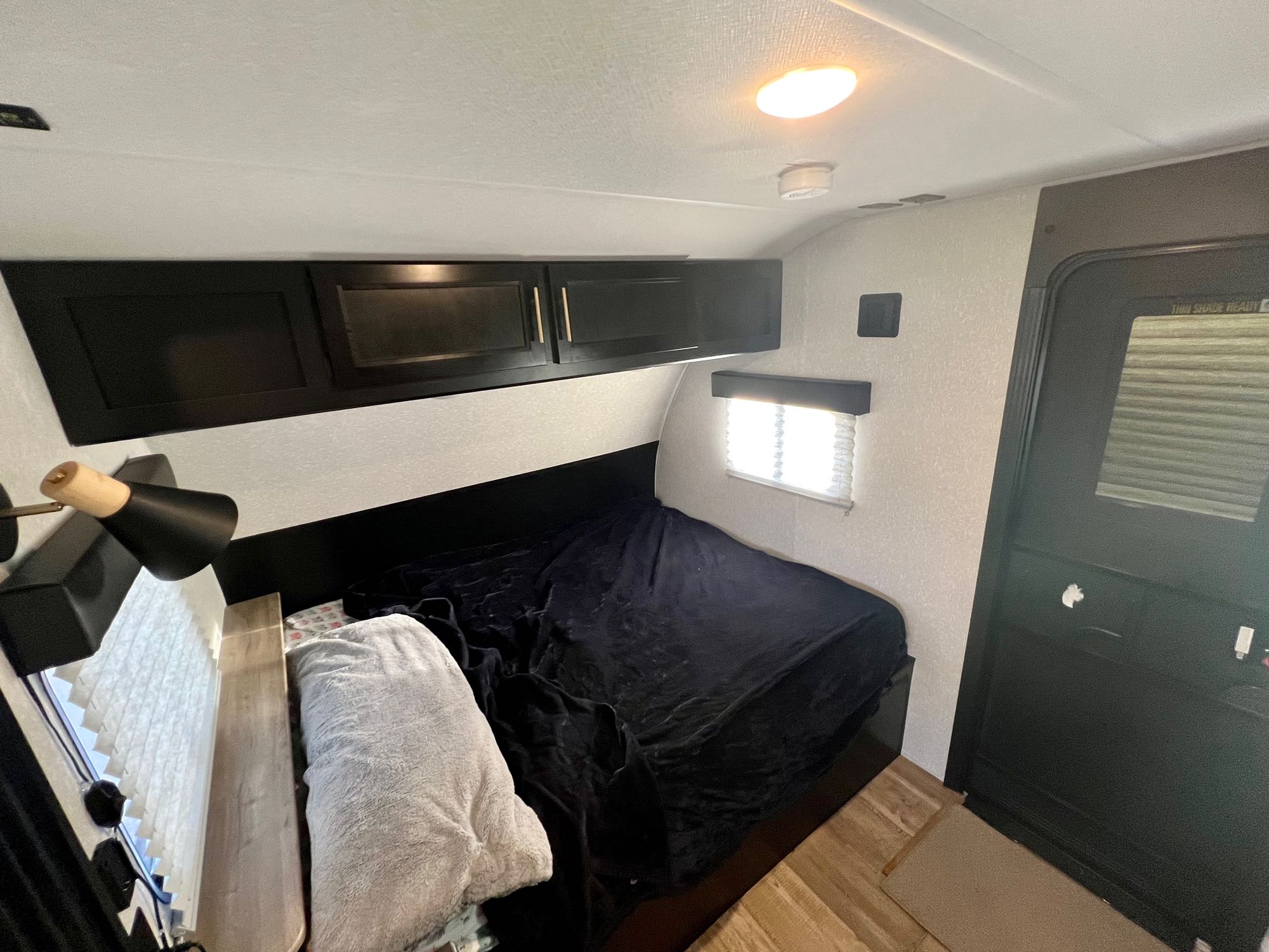 Inside an RV rental: a compact bedroom with a dark bed, overhead storage, and a small window for a cozy stay.. Forest River Cherokee Wolf Pup 2022