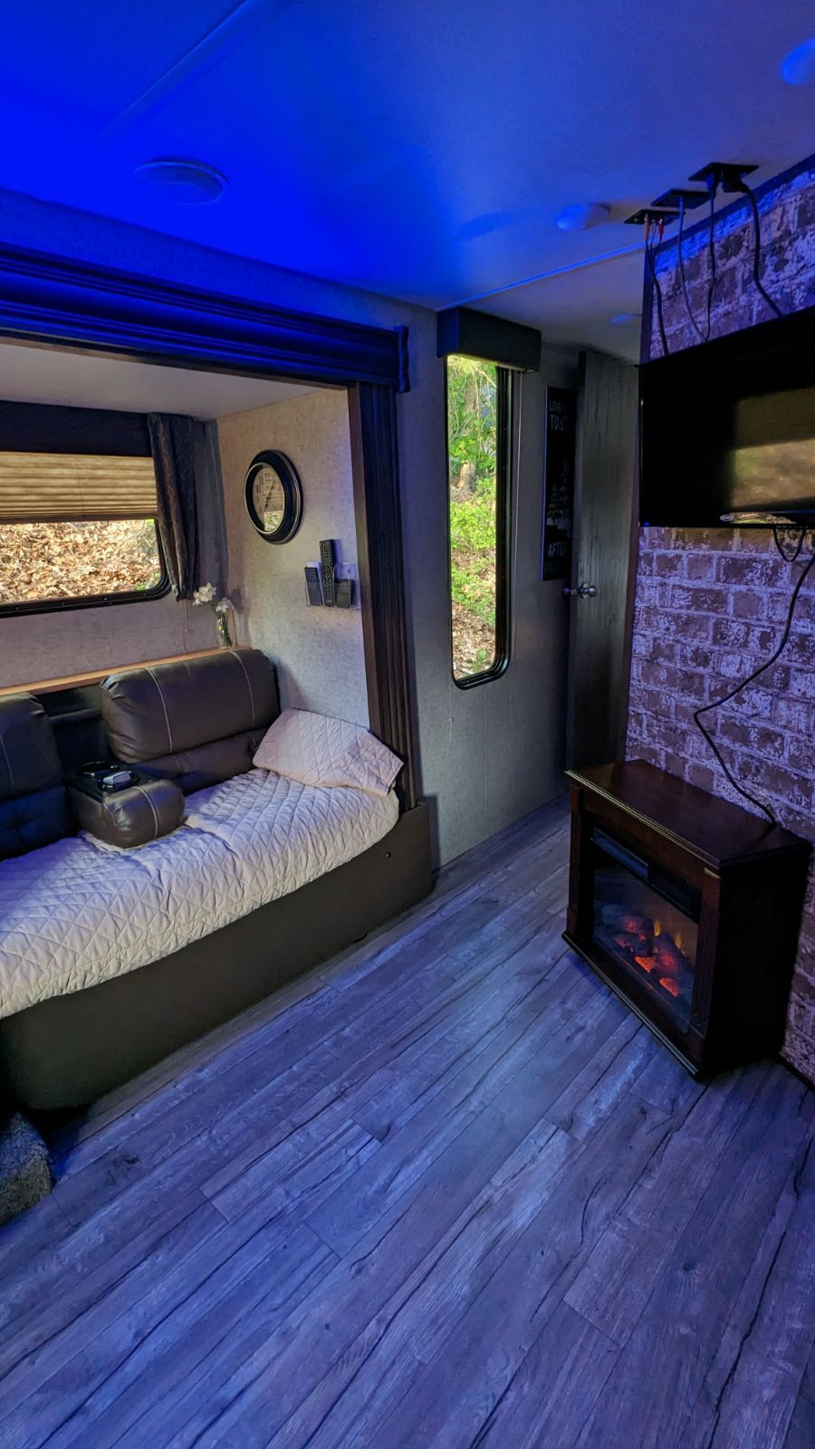 Inside a cozy **rv rental**: blue LED ceiling lights illuminate a sofa-bed, electric fireplace, and TV for home comforts.. Forest River Cherokee Grey Wolf 2018