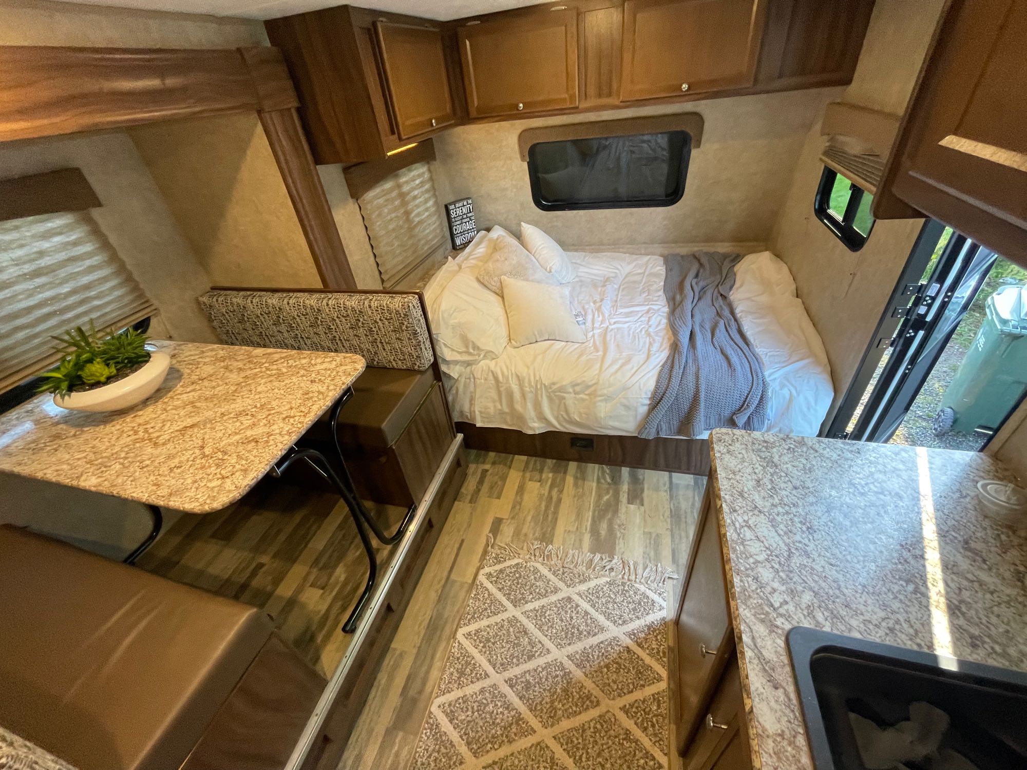 Bright rv rental interior with a cozy bed, dinette, and kitchen area. Ideal compact living space for adventures.. Forest River Viking 2018