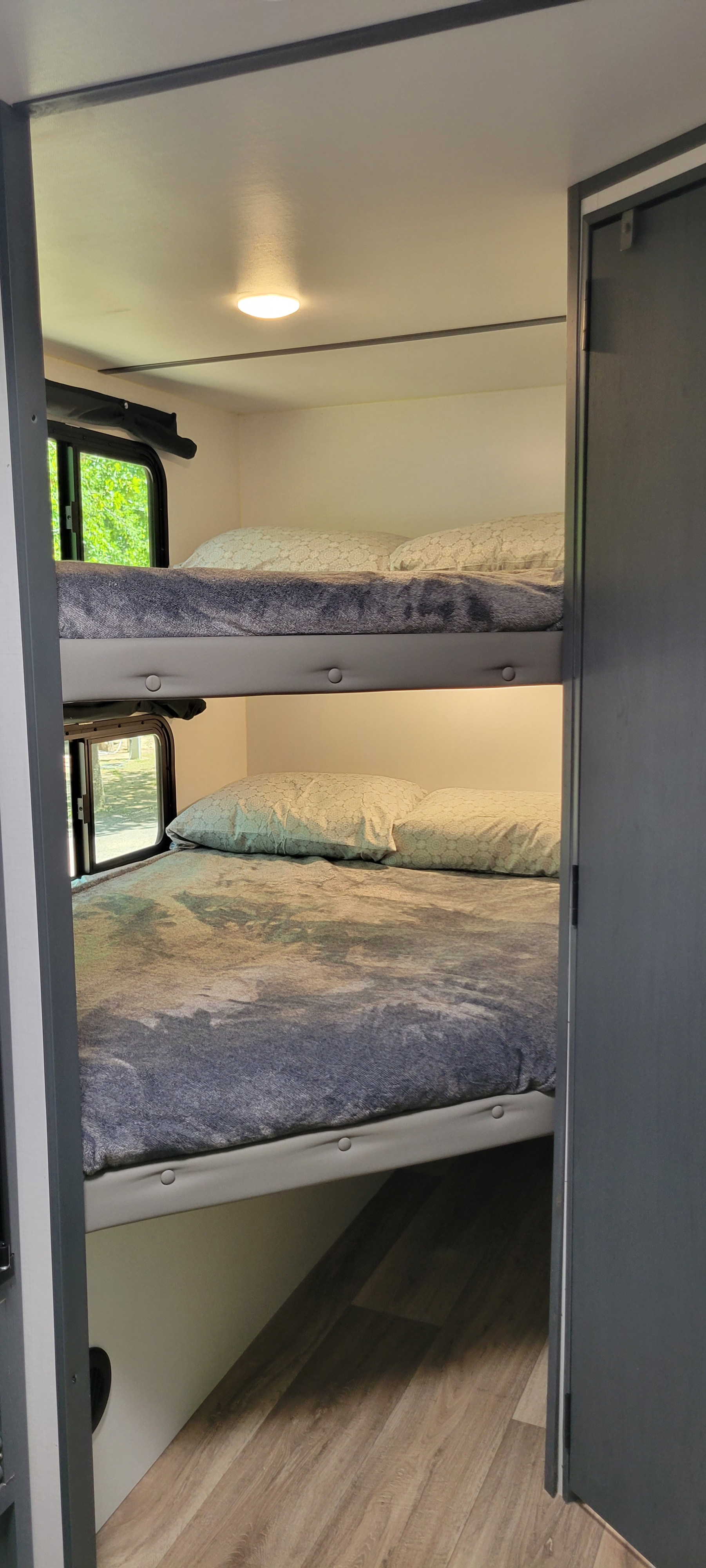 Interior of an RV rental: two bunk beds with pillows, blankets, windows, and under-bunk lighting for comfortable sleeping.. Keystone RV Bullet Crossfire 2022