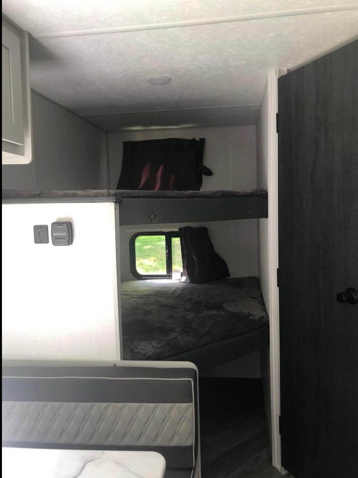 Inside an RV rental showing stacked bunk beds, a window with outdoor view, and a dinette.. Forest River Wildwood FSX Platinum 2021