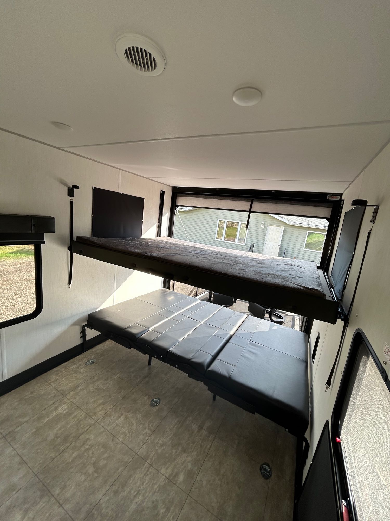 Spacious RV rental toy hauler interior with convertible bunk beds and open rear garage door for versatile use.. Forest River Vengeance 2022