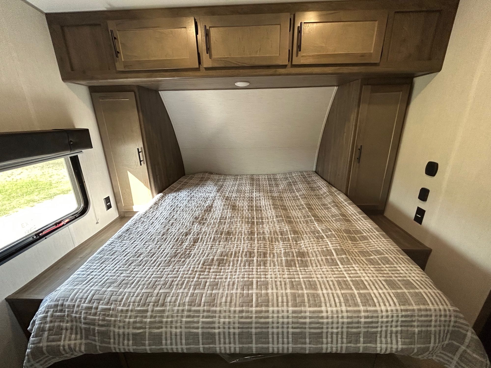 RV rental bedroom showcasing a plaid bed, overhead storage, and side cabinets, offering a functional and cozy sleeping area.. Forest River Vengeance 2022