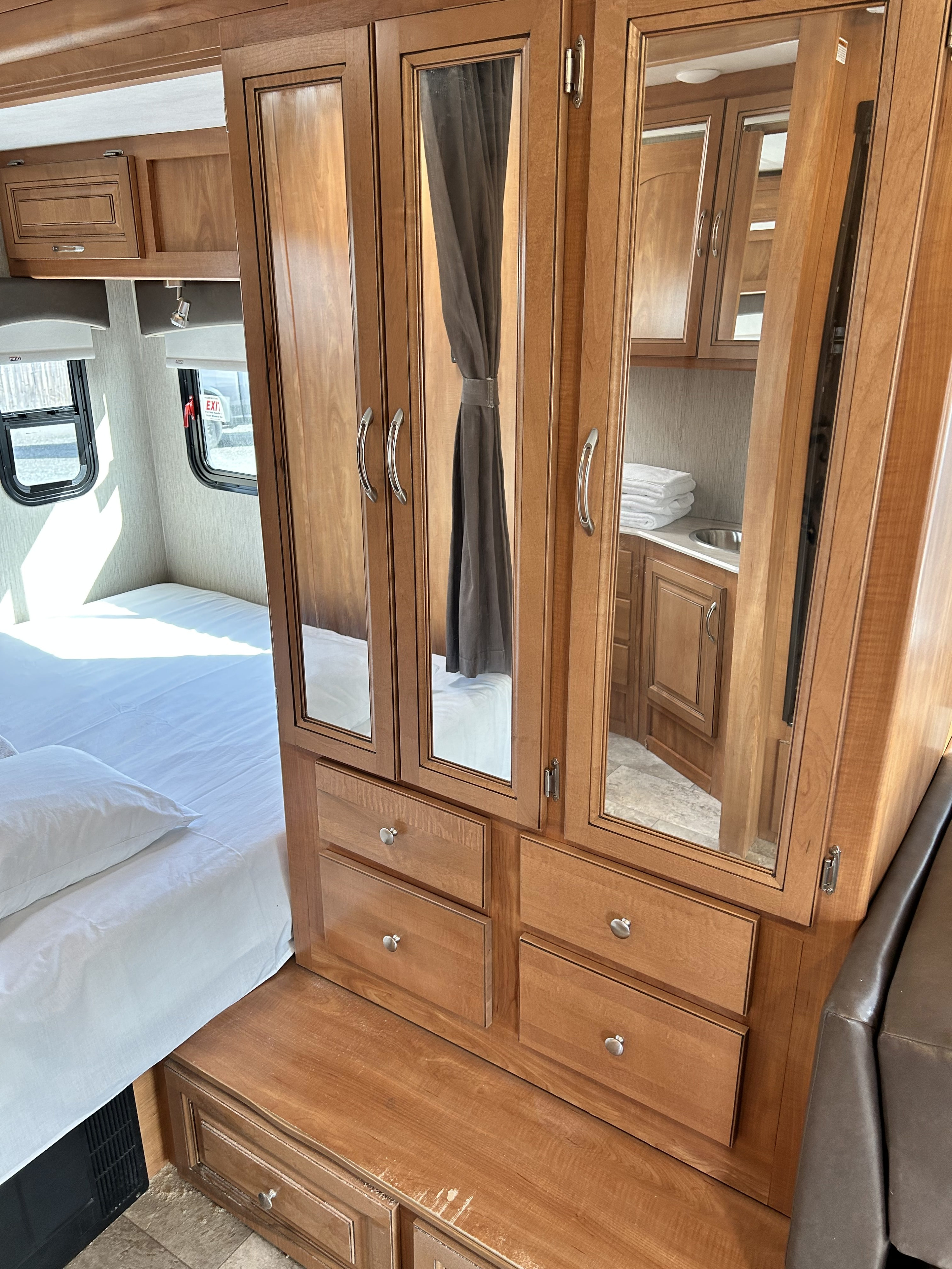 This RV rental features a cozy bedroom with mirrored storage & windows, plus a reflected view of the bathroom.. Nexus Phantom 2019