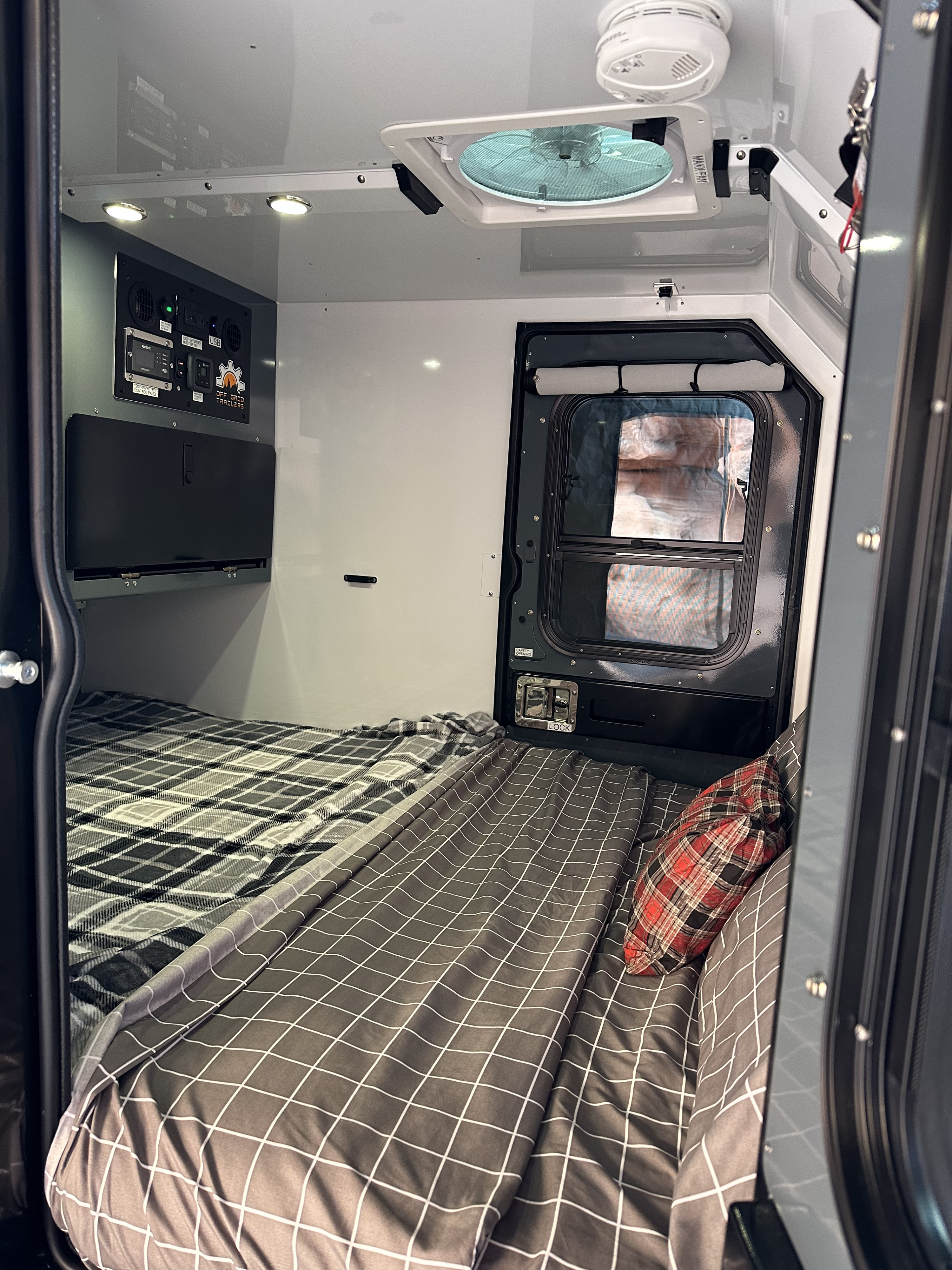 Cozy interior of an RV rental, featuring beds, control panel, and vent fan, ready for off-grid adventures.. Off Grid Trailers Off Grid Trailers Trailer 2022