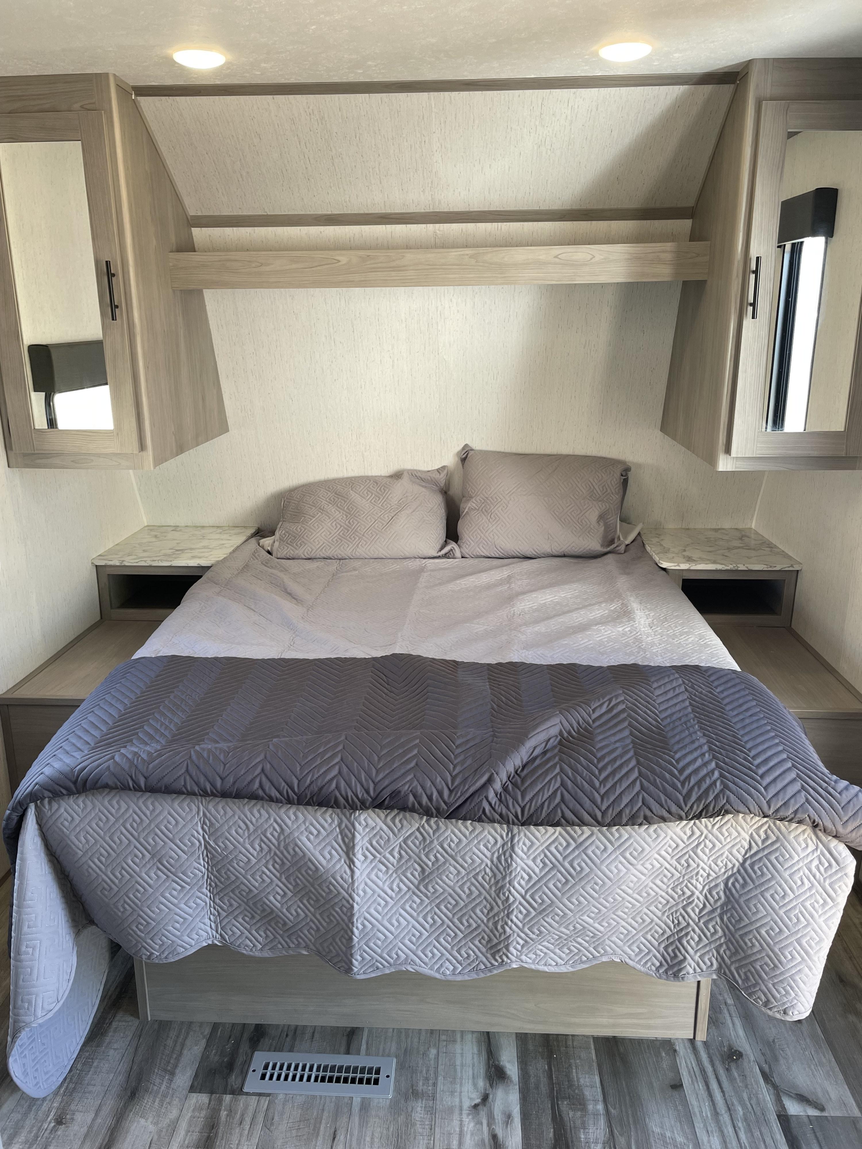 Cozy RV rental bedroom with a comfortable bed, built-in cabinets, and warm lighting, ideal for your travels.. Dutchmen Coleman Lantern LT 2022