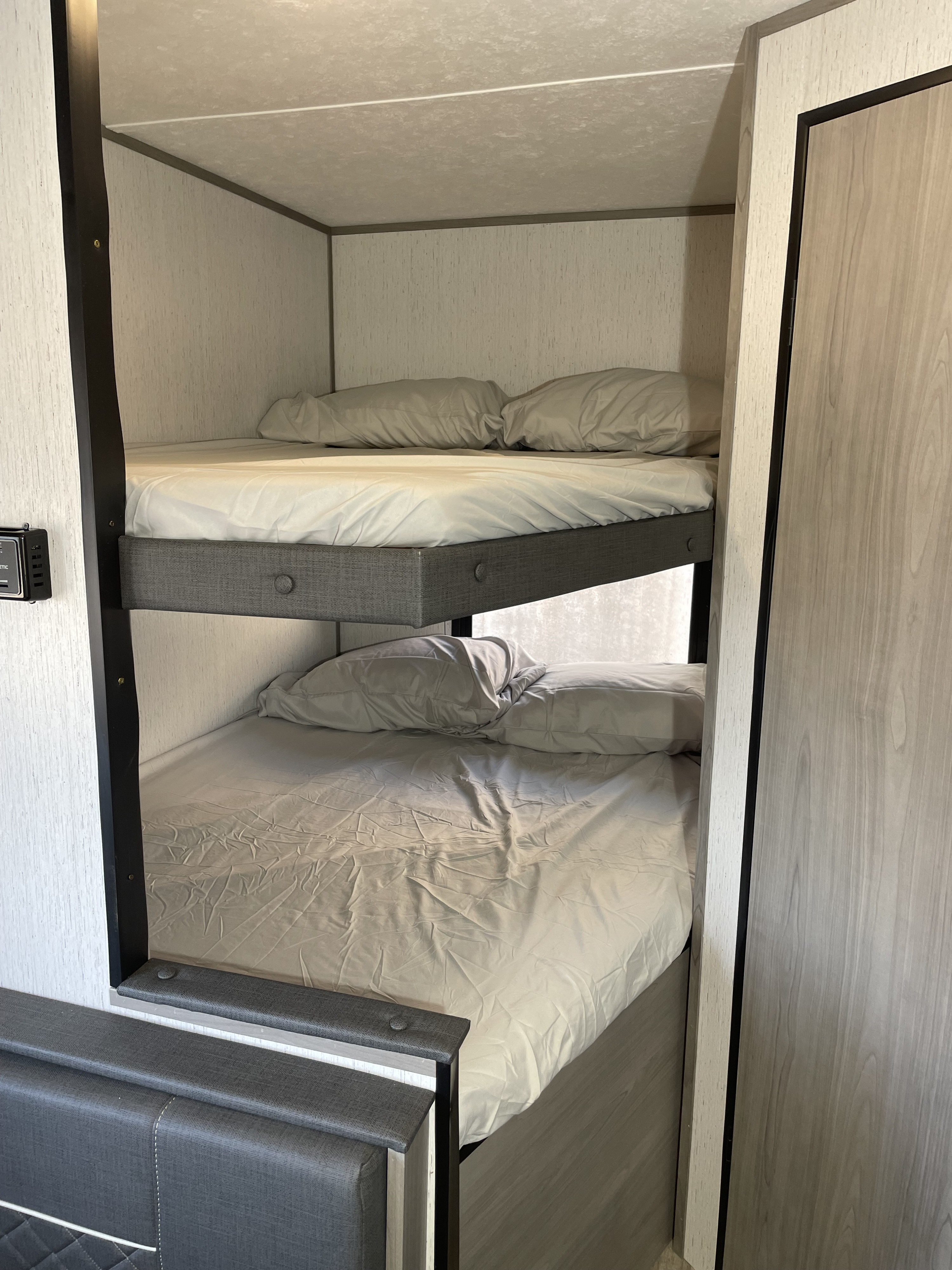 Explore this RV rental's cozy bunk beds, complete with light bedding and upholstered frames, offering comfortable sleeping for your trip.. Dutchmen Coleman Lantern LT 2022