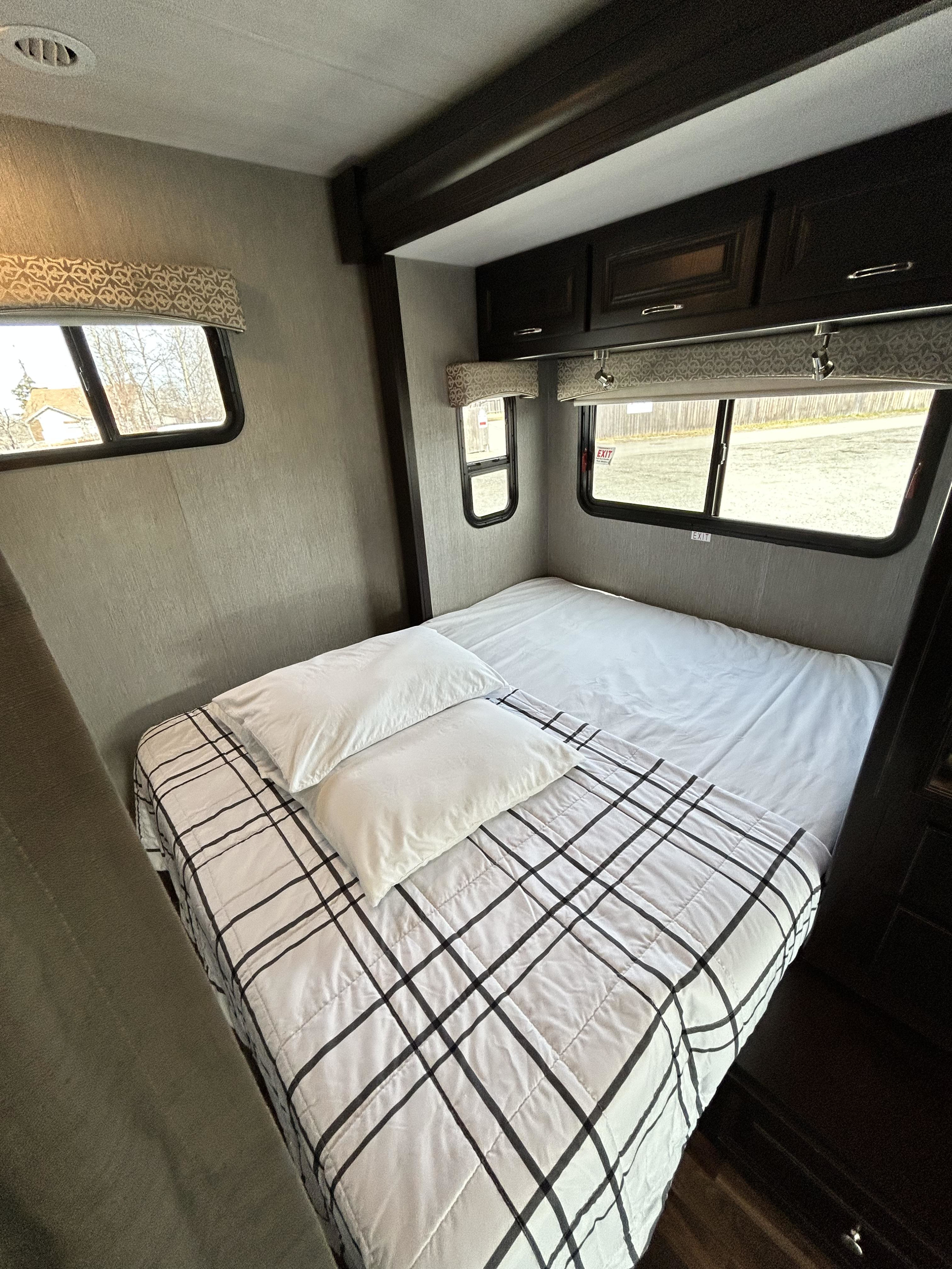Comfortable RV rental bedroom featuring a tidy bed, overhead cabinets, and multiple windows for natural light.. Nexus Phantom 2020