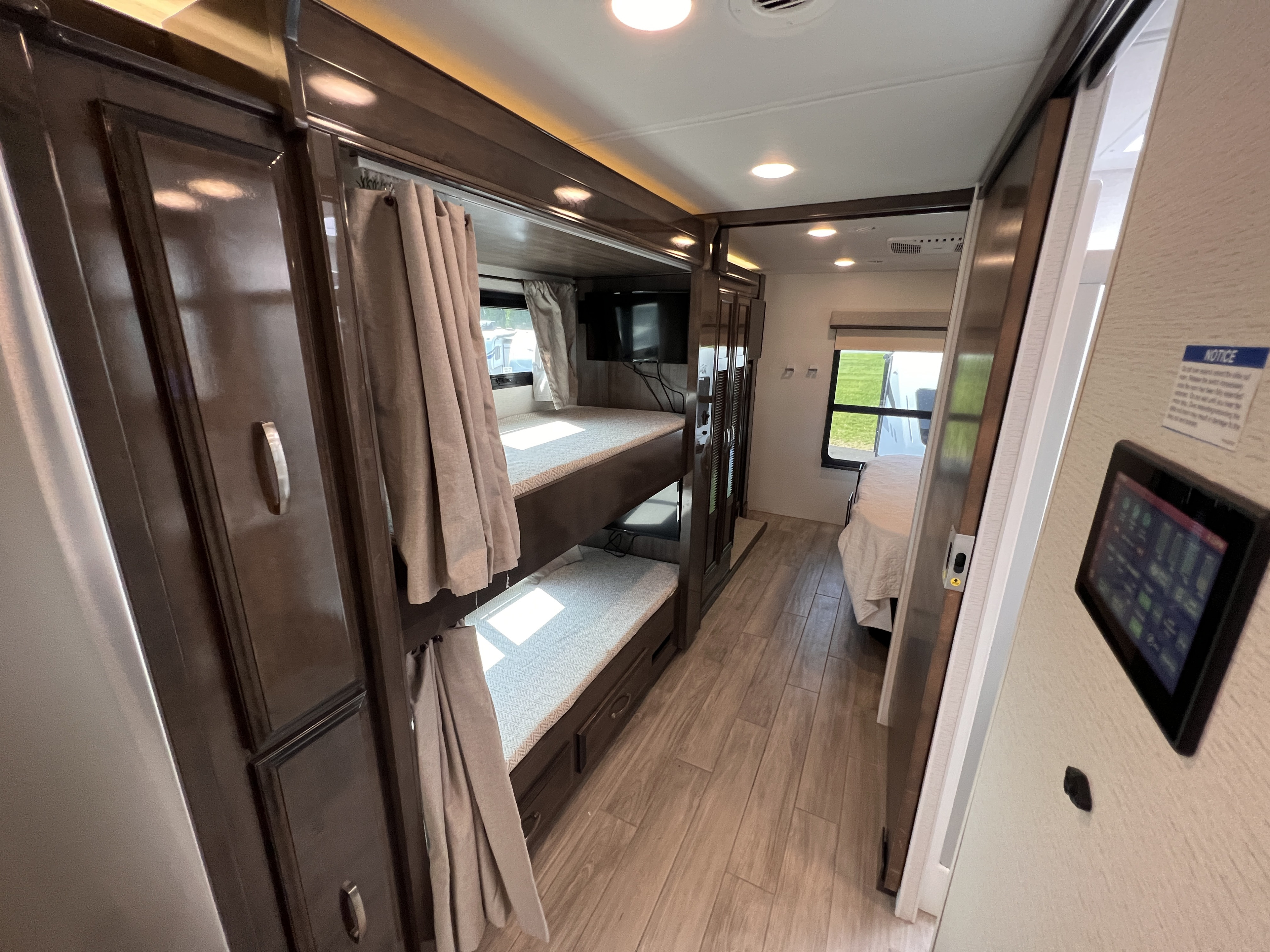 Inside this RV rental: spacious interior with dark wood bunk beds, privacy curtains, and a bright hallway leading to more sleeping areas.. Entegra Coach Accolade XL 37L  Super-C 2023