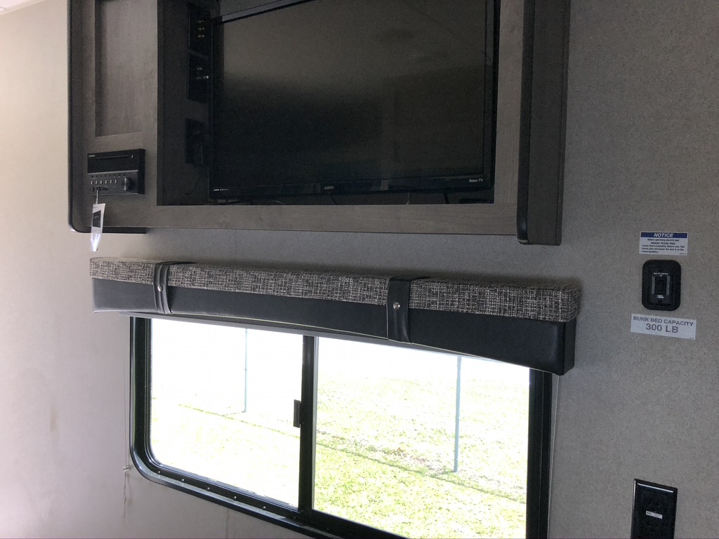 RV rental interior featuring a mounted TV, stereo, window, and bunk bed capacity notice. Comfort for your trip!. Forest River Palomino Puma XLE Toy Hauler 2019