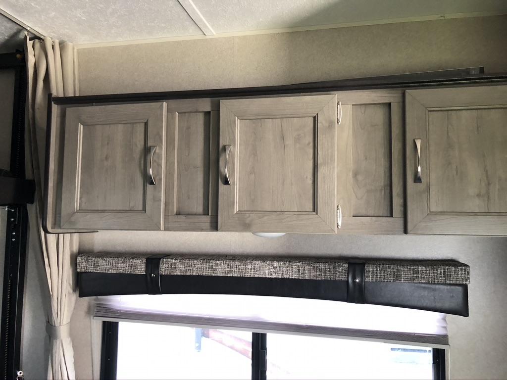 Modern overhead storage cabinets, window blinds, and valance visible in an RV rental interior.. Forest River Palomino Puma XLE Toy Hauler 2019