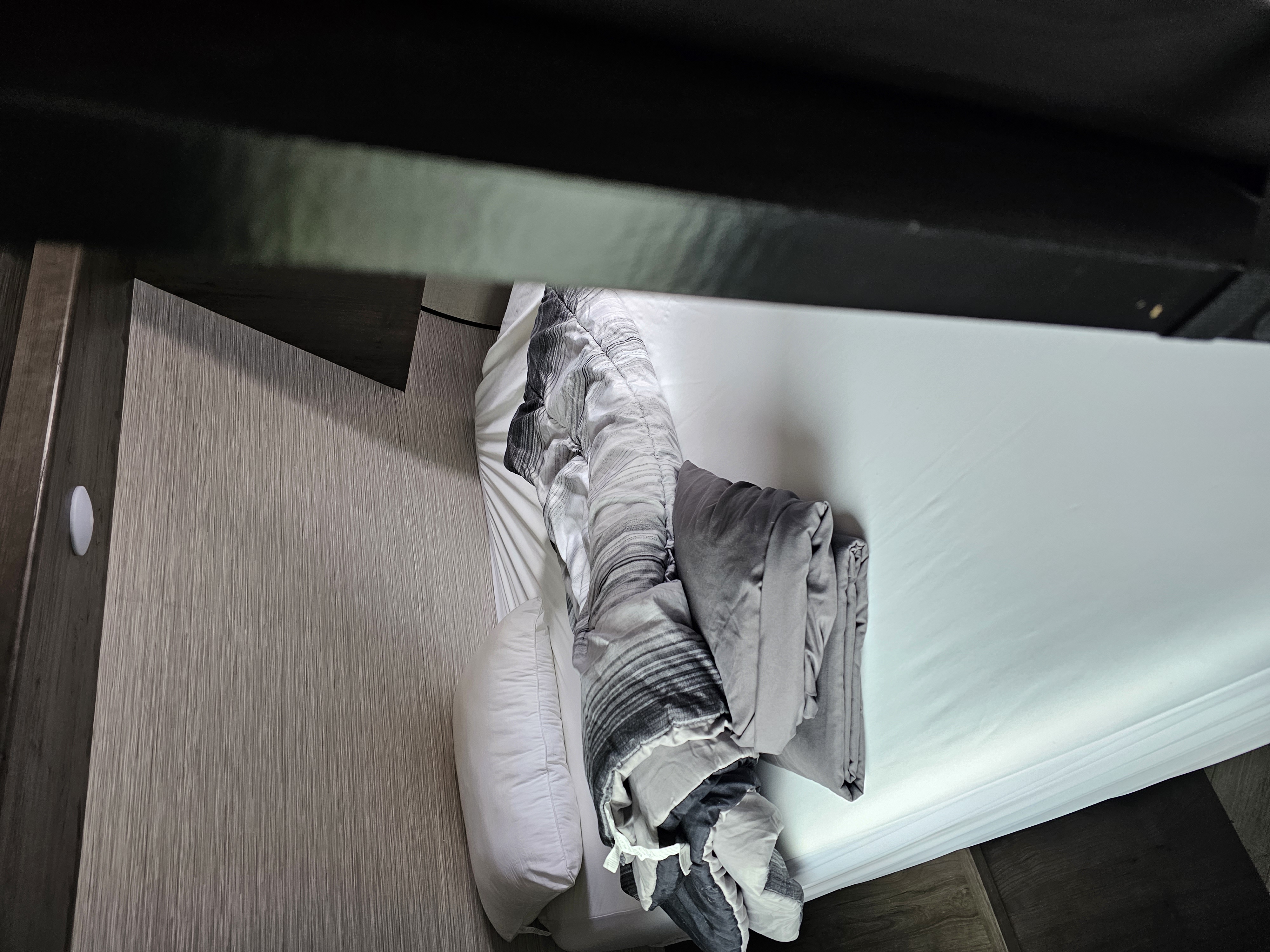 Cozy RV rental bedroom with a neatly made bed featuring grey bedding, wood paneling, and an overhead bunk. Ideal for travel.. Highland Ridge RV Olympia 2022