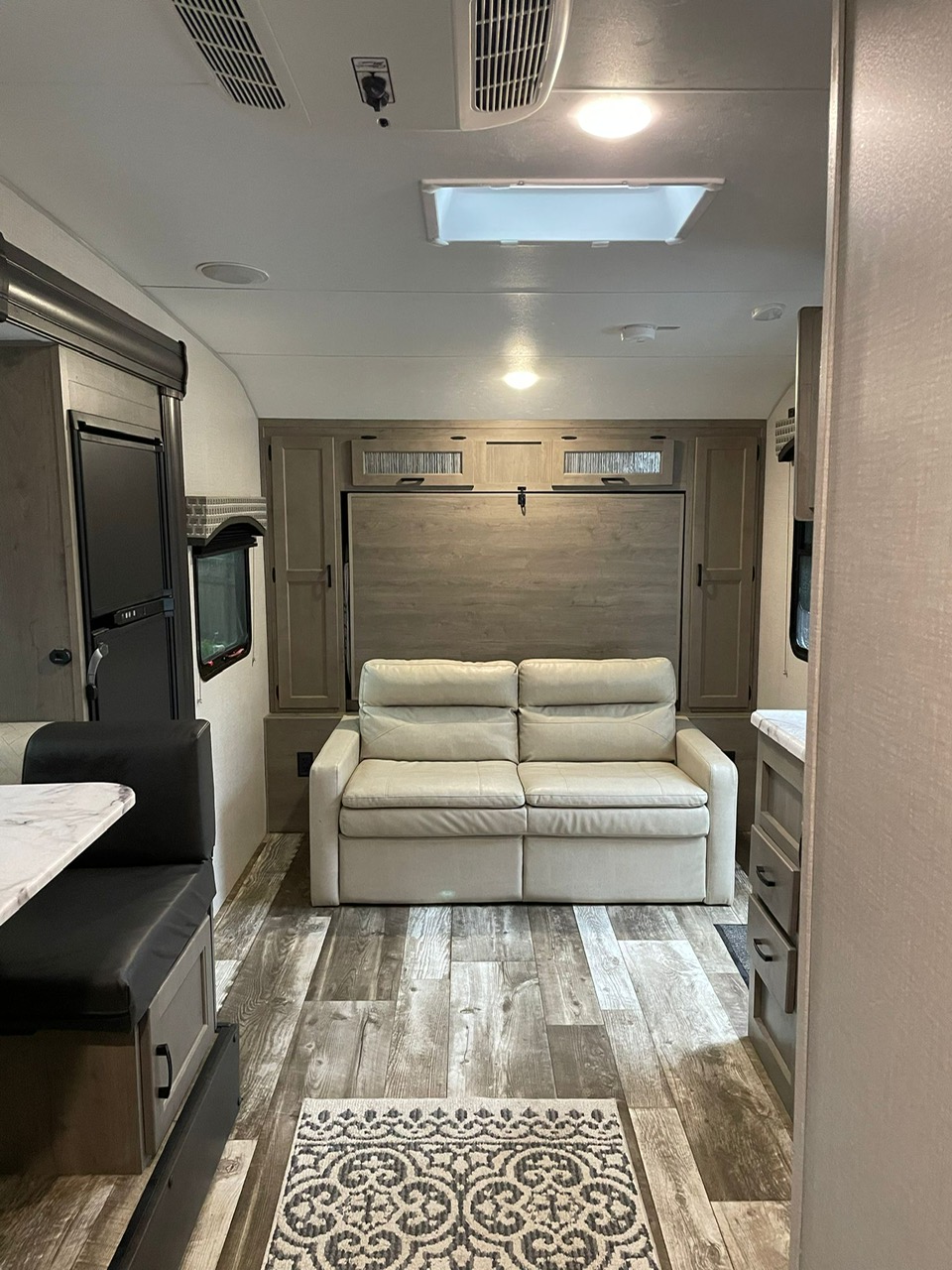 Step inside this RV rental's spacious living area, featuring a light sofa bed, dinette, and wood-look flooring.. Sonic Sonic Trailer 2020