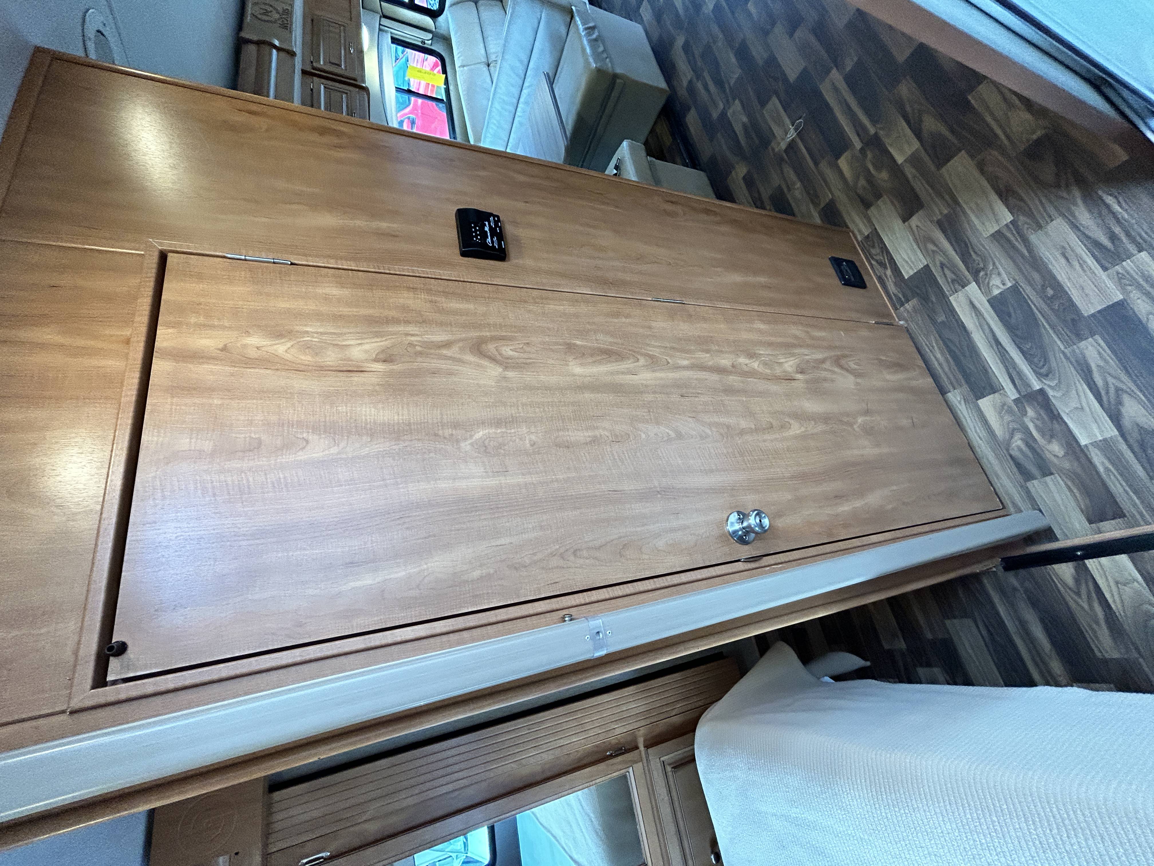 RV rental bedroom with light wood storage, control panel, and geometric patterned floor.. Nexus Phantom 2019