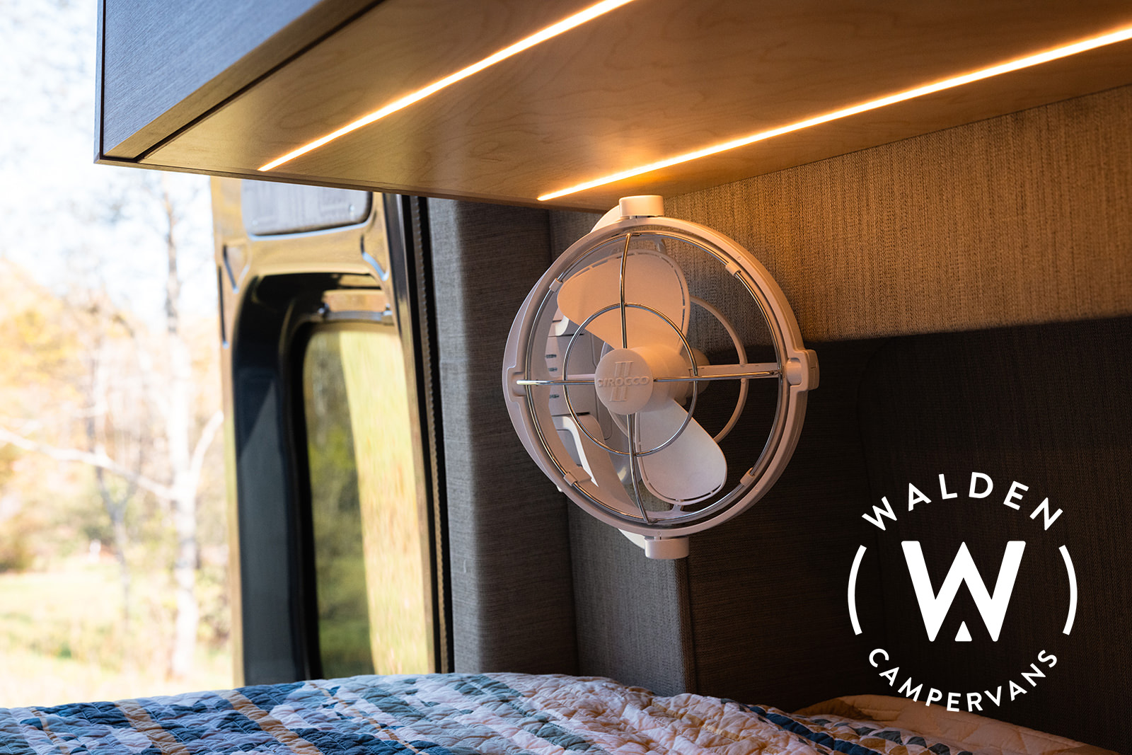 RV rental comfort: Enjoy the compact fan & warm LED lighting over a cozy bed in this Walden campervan interior.. Mercedes-Benz Sprinter 2023