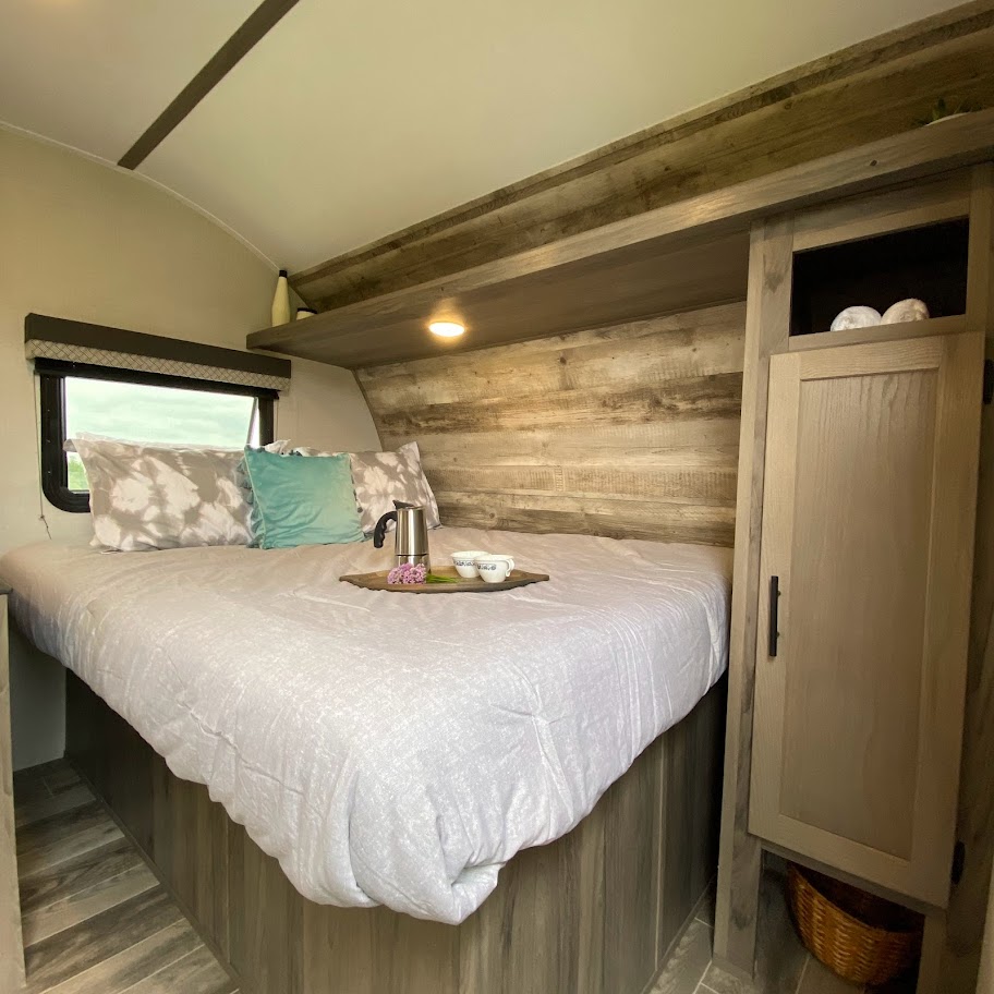 Comfortable RV rental bedroom with wood paneling, plush bed, and breakfast setup for a relaxing travel stay.. Gulf Stream Conquest Lite 2023