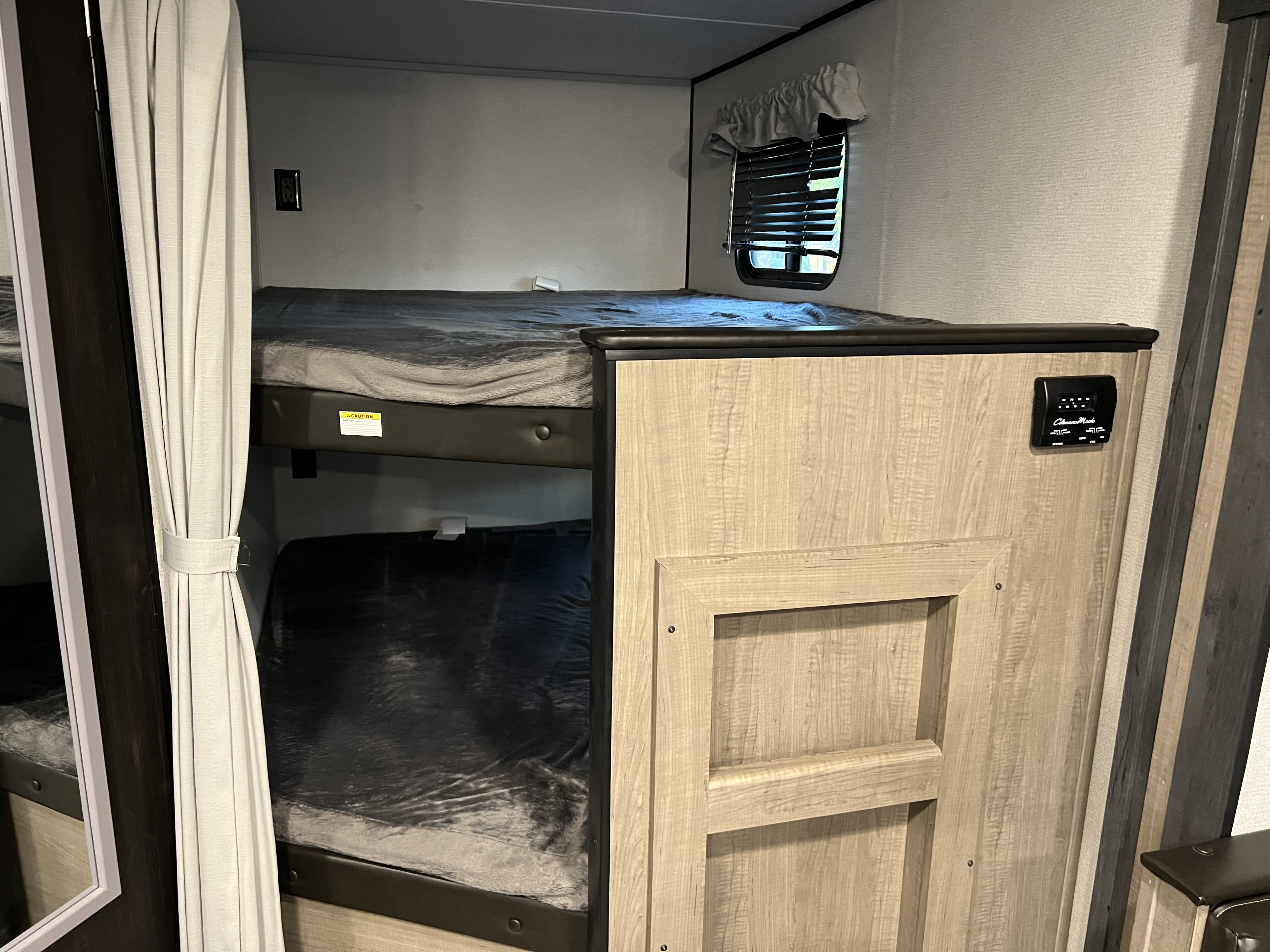 Compact RV rental interior featuring stacked bunk beds, a window, and control panel.. Keystone RV Other 2021