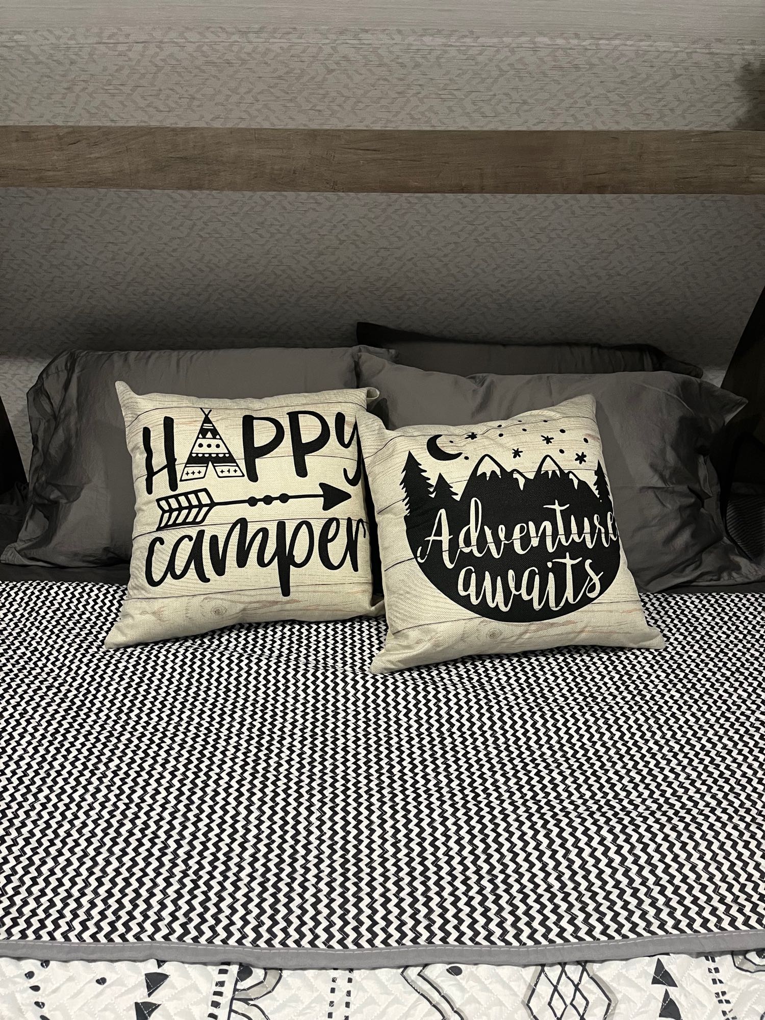 RV rental bed features "Happy Camper" and "Adventure Awaits" pillows on black/white bedding, ready for travel.. Forest River Salem Cruise Lite 2022