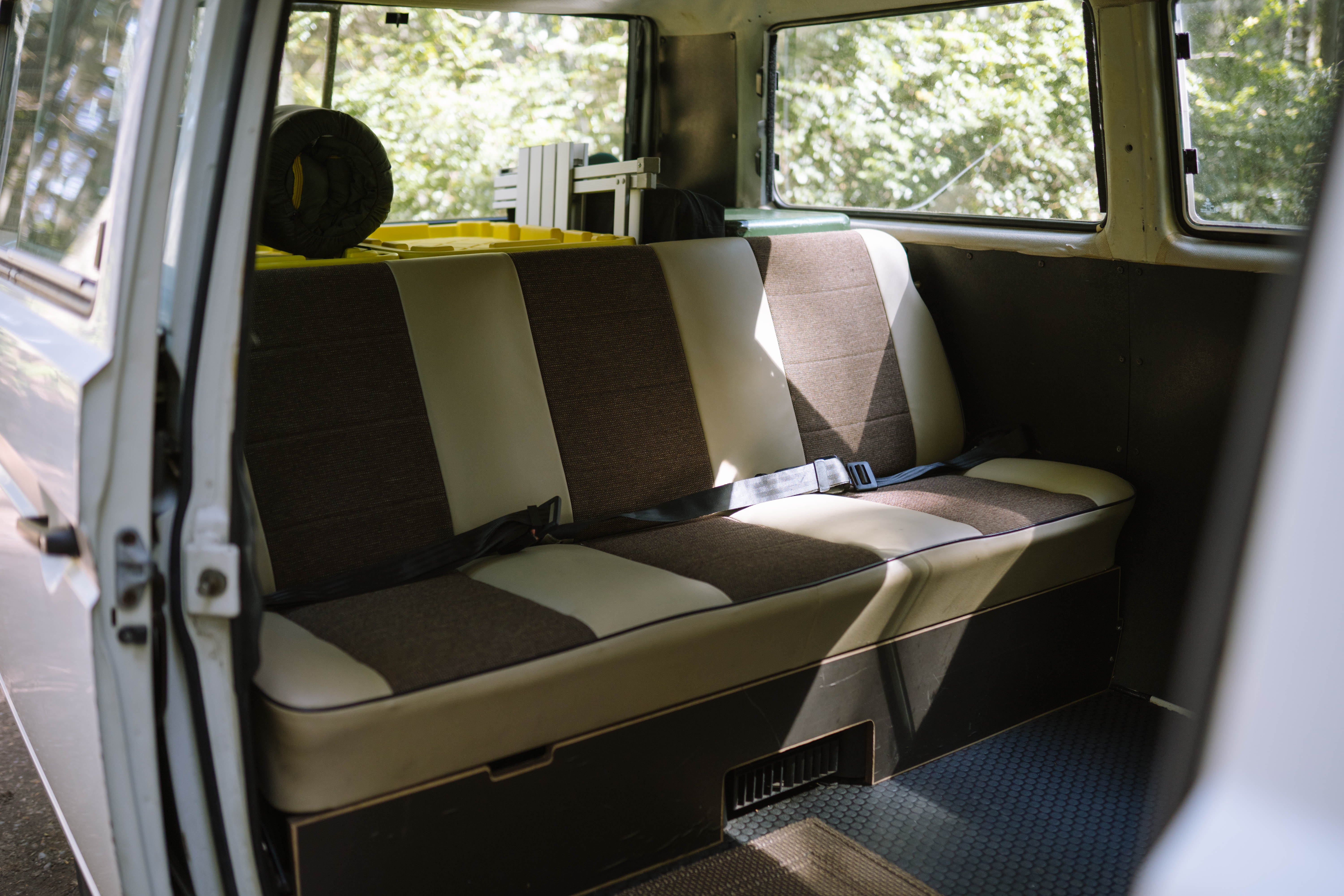RV rental interior: A two-tone bench seat with seatbelts and storage, bathed in sunlight. Ready for adventure!. Volkswagen Syncro 1987