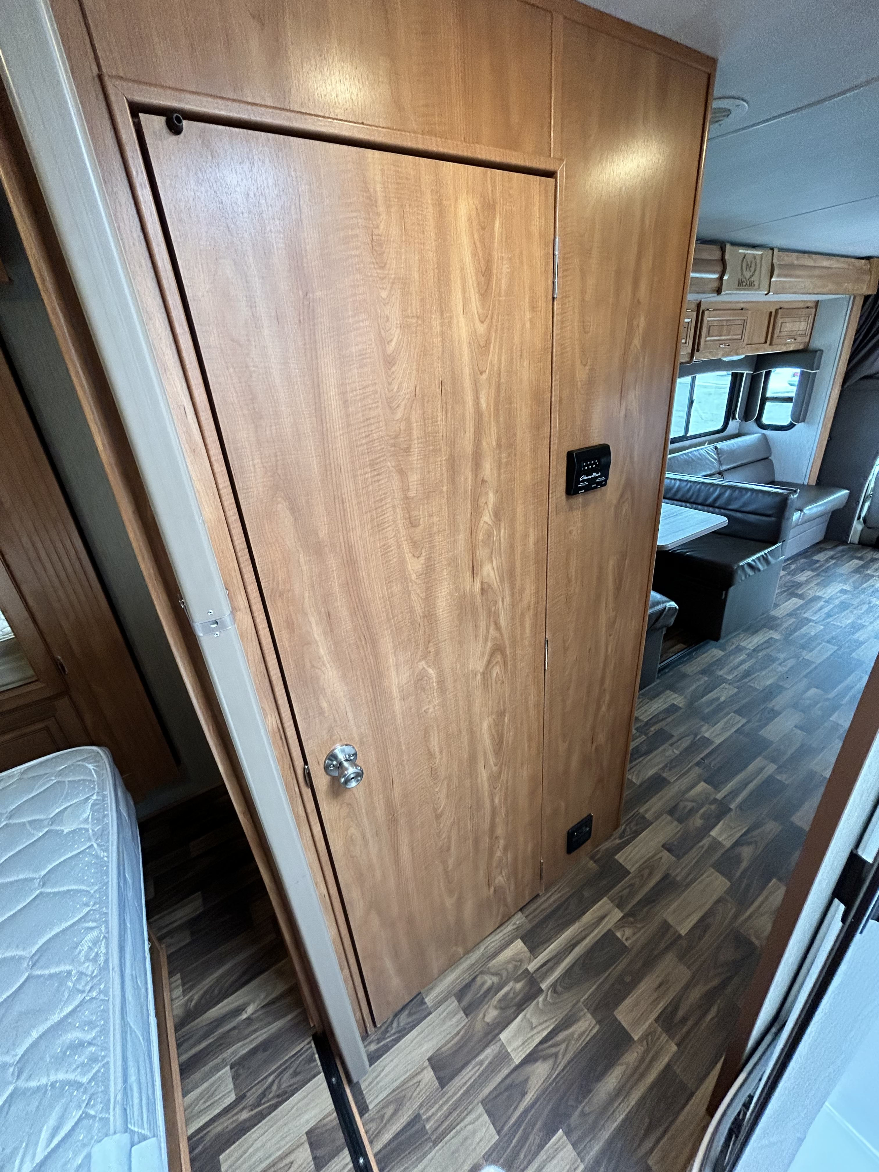 Inside this RV rental: light wood interior with control panel, dining booth, and patterned wood flooring.. Nexus Phantom 2019