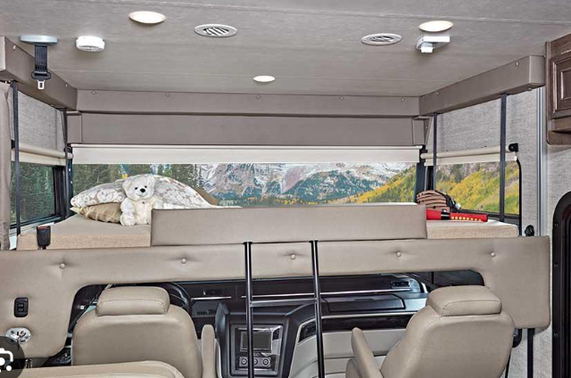 Explore an RV rental's cozy interior, featuring an overhead bunk with a scenic mountain backdrop. Perfect for family adventures.. Entegra Coach Vision 2021