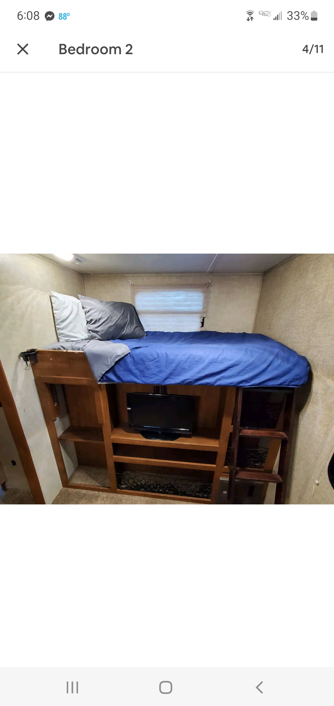 Compact RV rental bedroom with a loft bed, built-in TV, shelves, and ladder, optimizing space in a cozy setting.. Keystone Sprinter 2014
