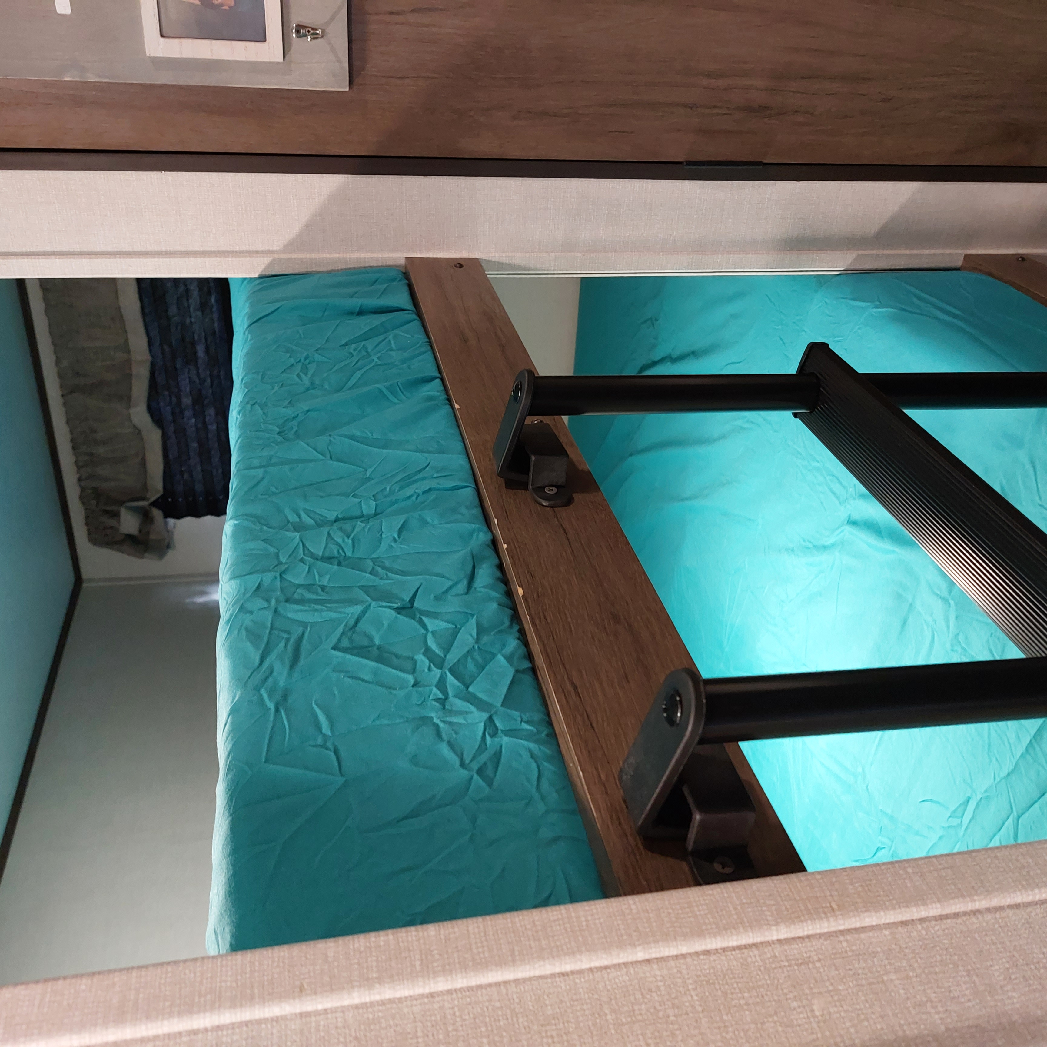 Teal bunk bed with a black ladder inside an RV rental. A comfortable and compact sleeping area.. Avenger Avenger Trailer 2021