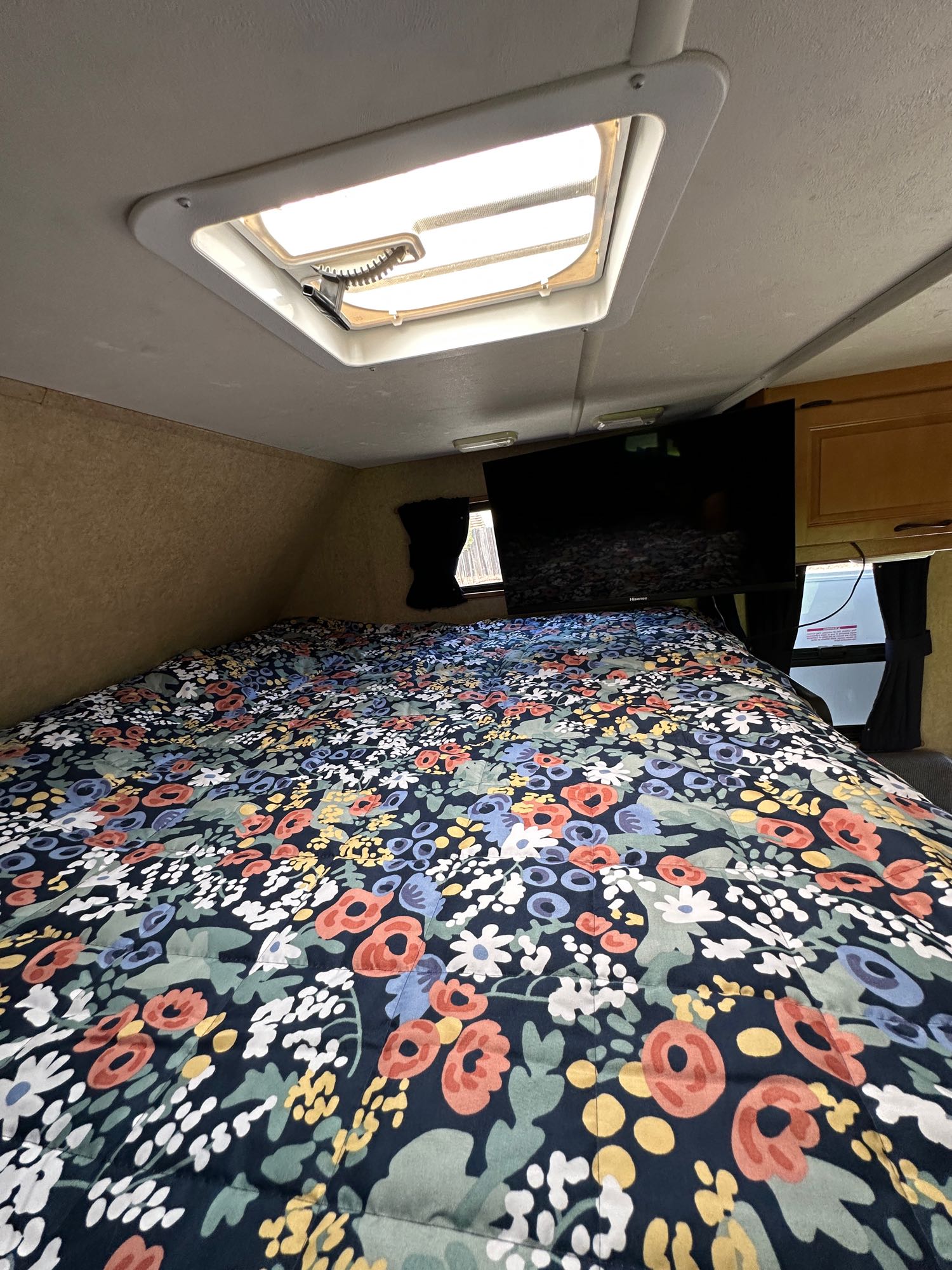 Cozy RV rental bedroom with floral bed, skylight, and TV. Ideal for comfortable travel and rest.. Thor Motor Coach Four Winds Majestic 2015