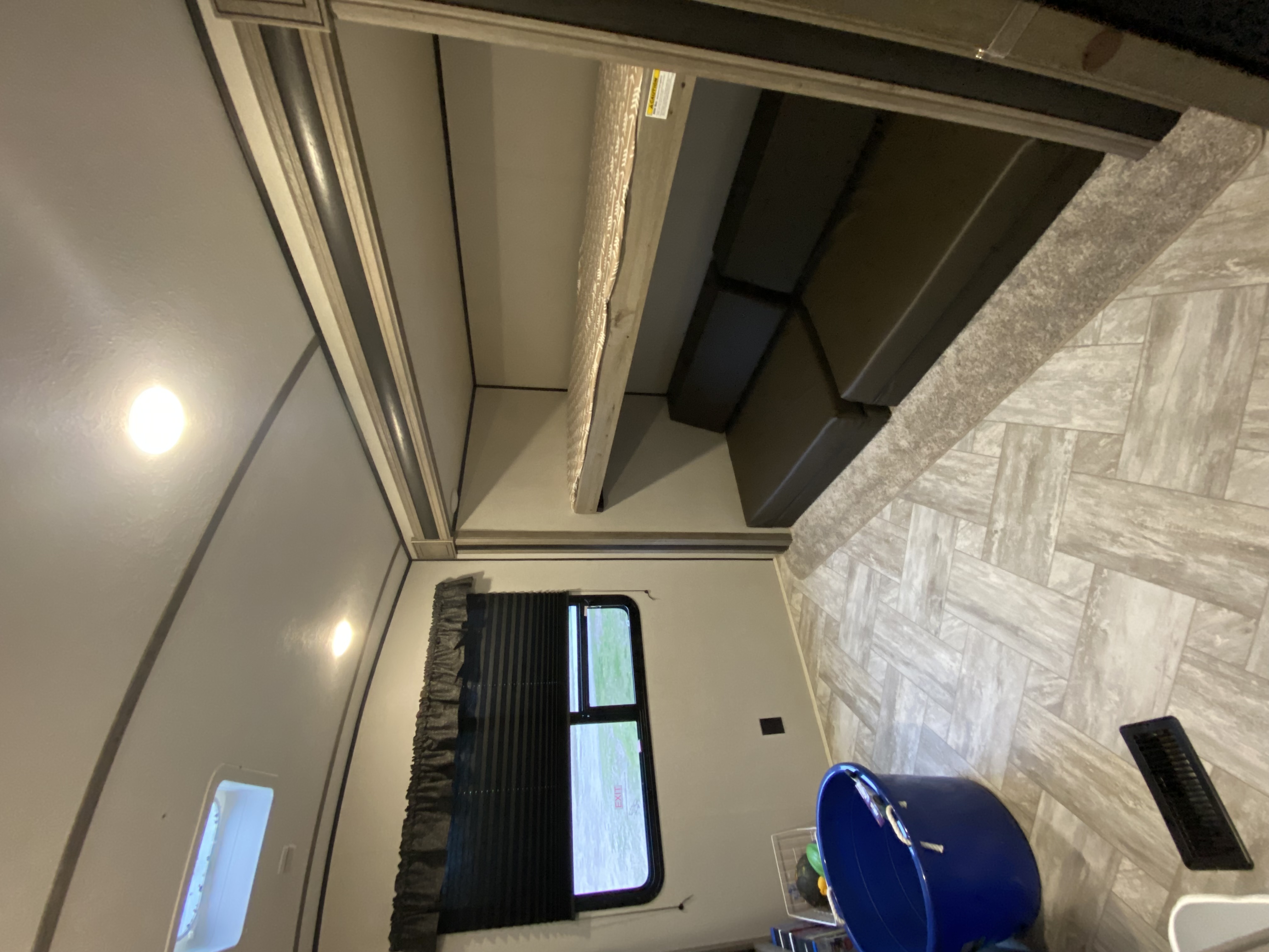 View inside an RV rental, highlighting bunk beds, a dinette, and bright ceiling lights, with a window on the left.. Keystone RV Springdale 2021