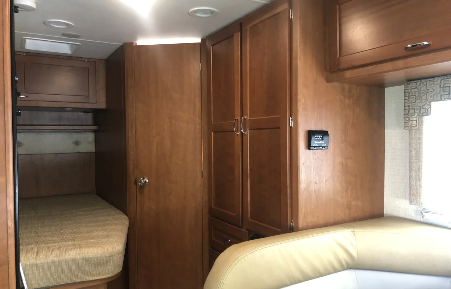 RV rental interior featuring bunk beds, light wood cabinets, a thermostat, and comfortable seating.. Winnebago Minnie Winnie 2016