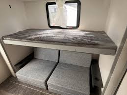 RV rental interior: A top bunk bed with mattress above two gray modular seating units, ideal for family sleeping.. Forest River Vibe 2022