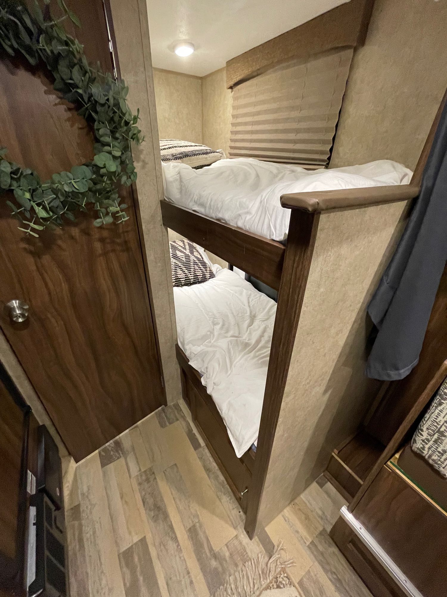An RV rental's cozy interior, showing sturdy bunk beds with white linens and wood-look flooring.. Forest River Viking 2018