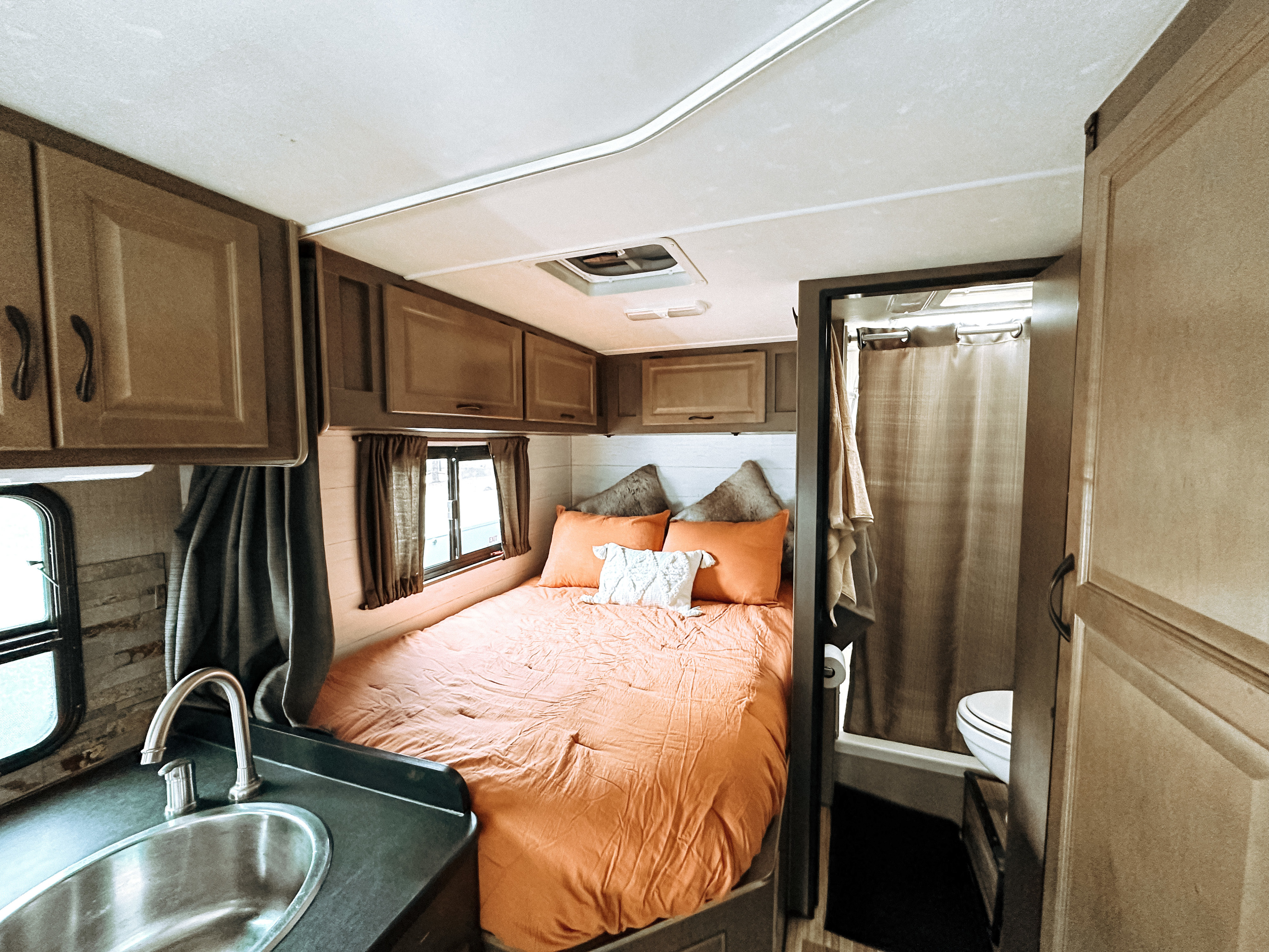 Step inside this functional rv rental featuring a comfy bed, compact kitchen area with a sink, and an adjacent bathroom.. Thor Majestic 2019